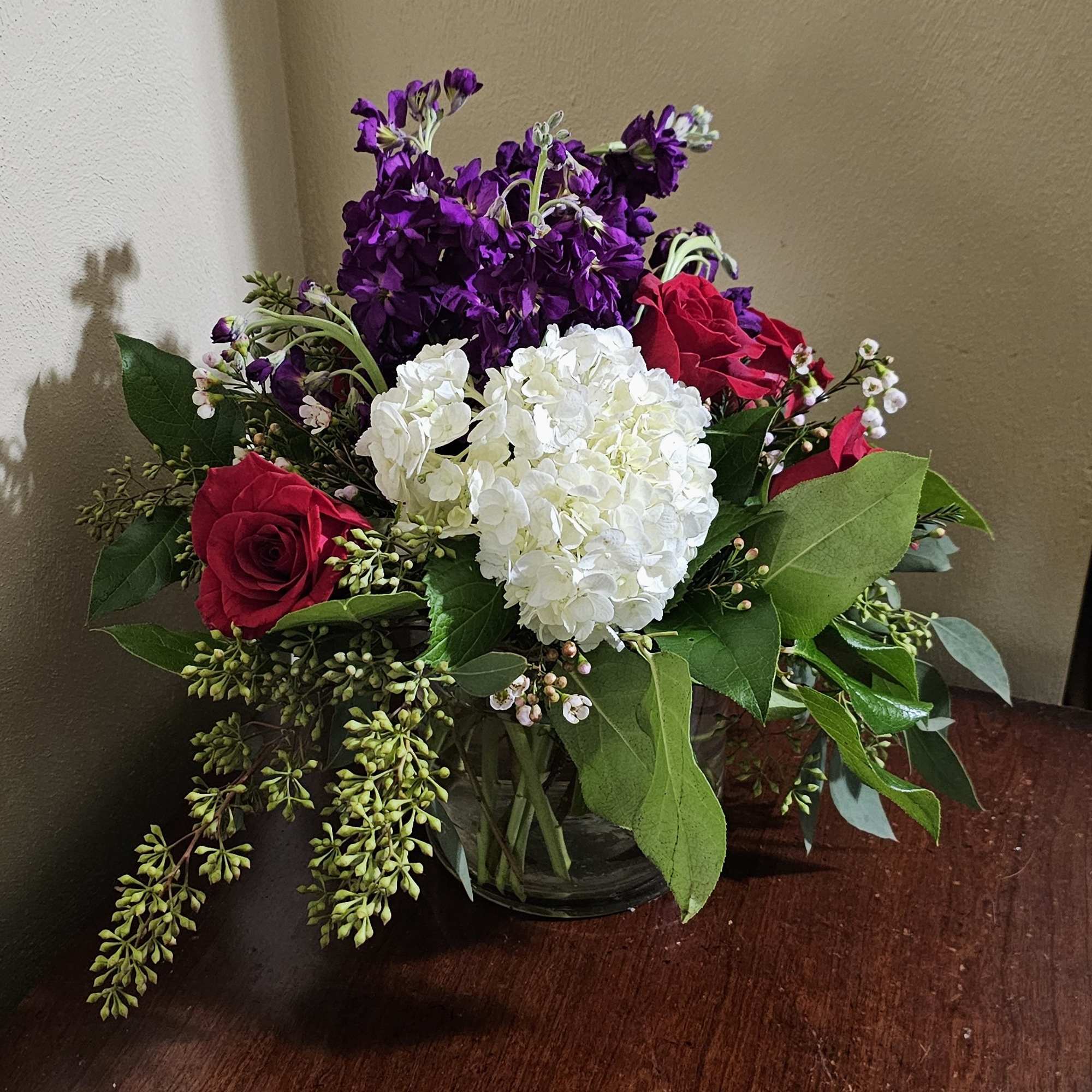 All around arrangement with royal colors of love in a cylindrical glass