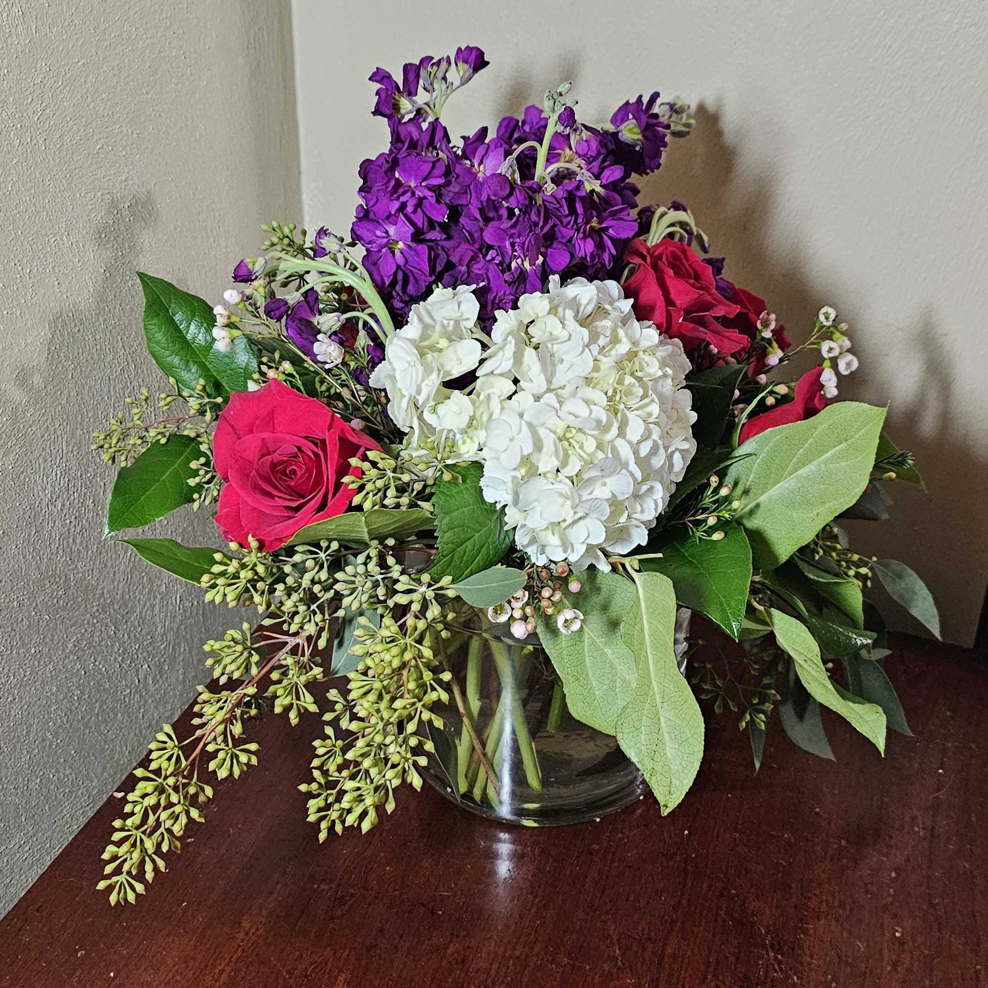 All around arrangement with royal colors of love in a cylindrical glass