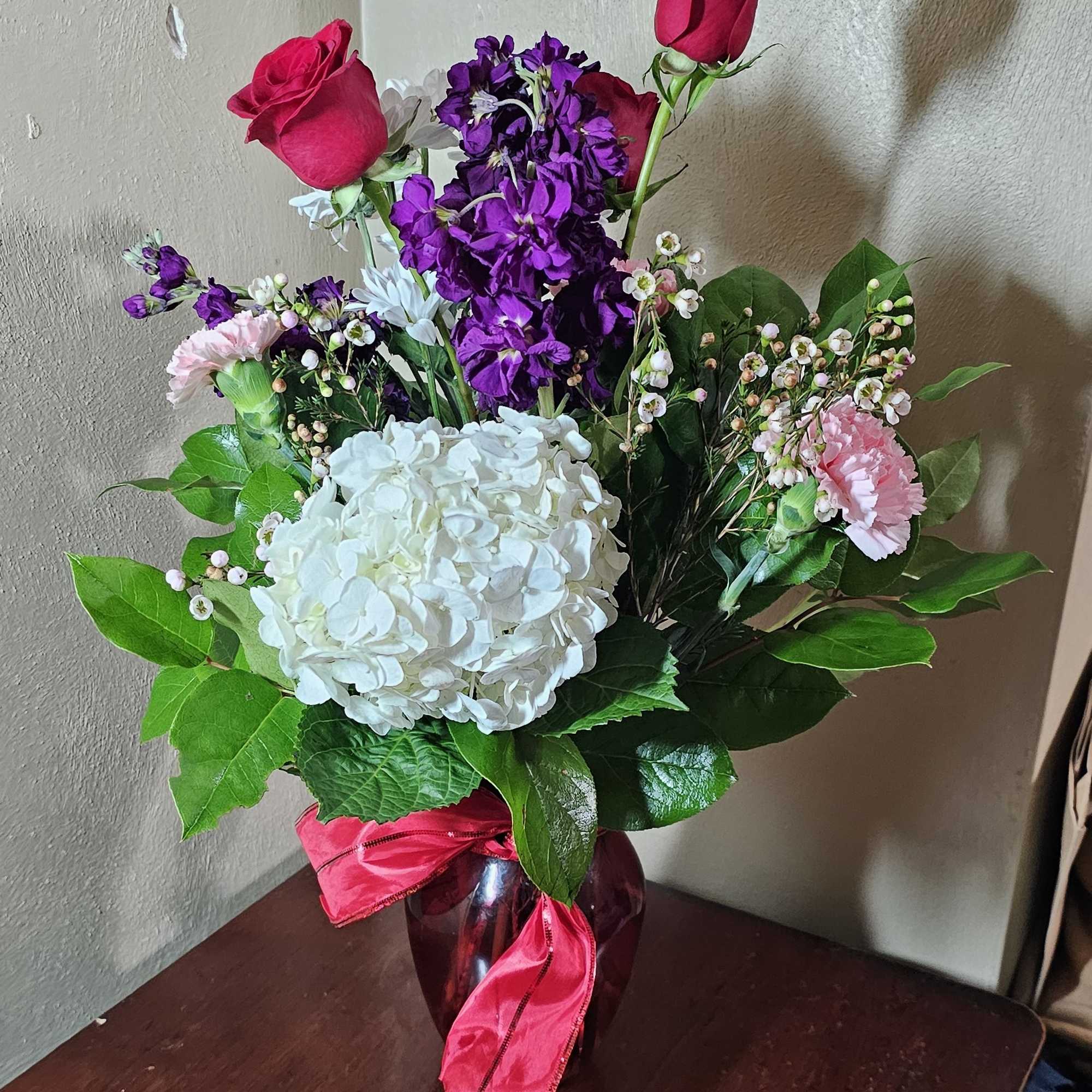 Red ruby vase filled with a variety of flowers representing Valentine&#039;s Days