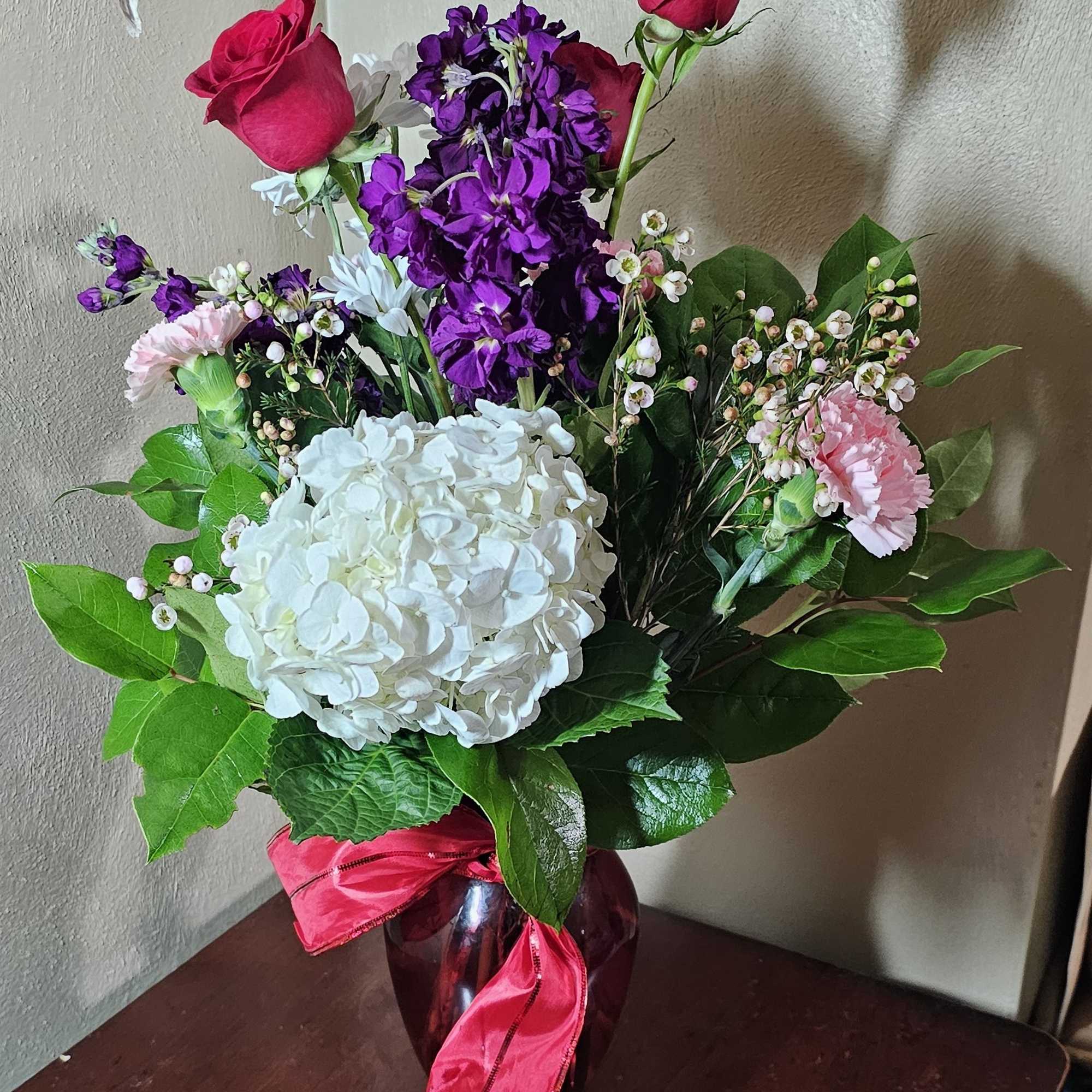 Red ruby vase filled with a variety of flowers representing Valentine&#039;s Days