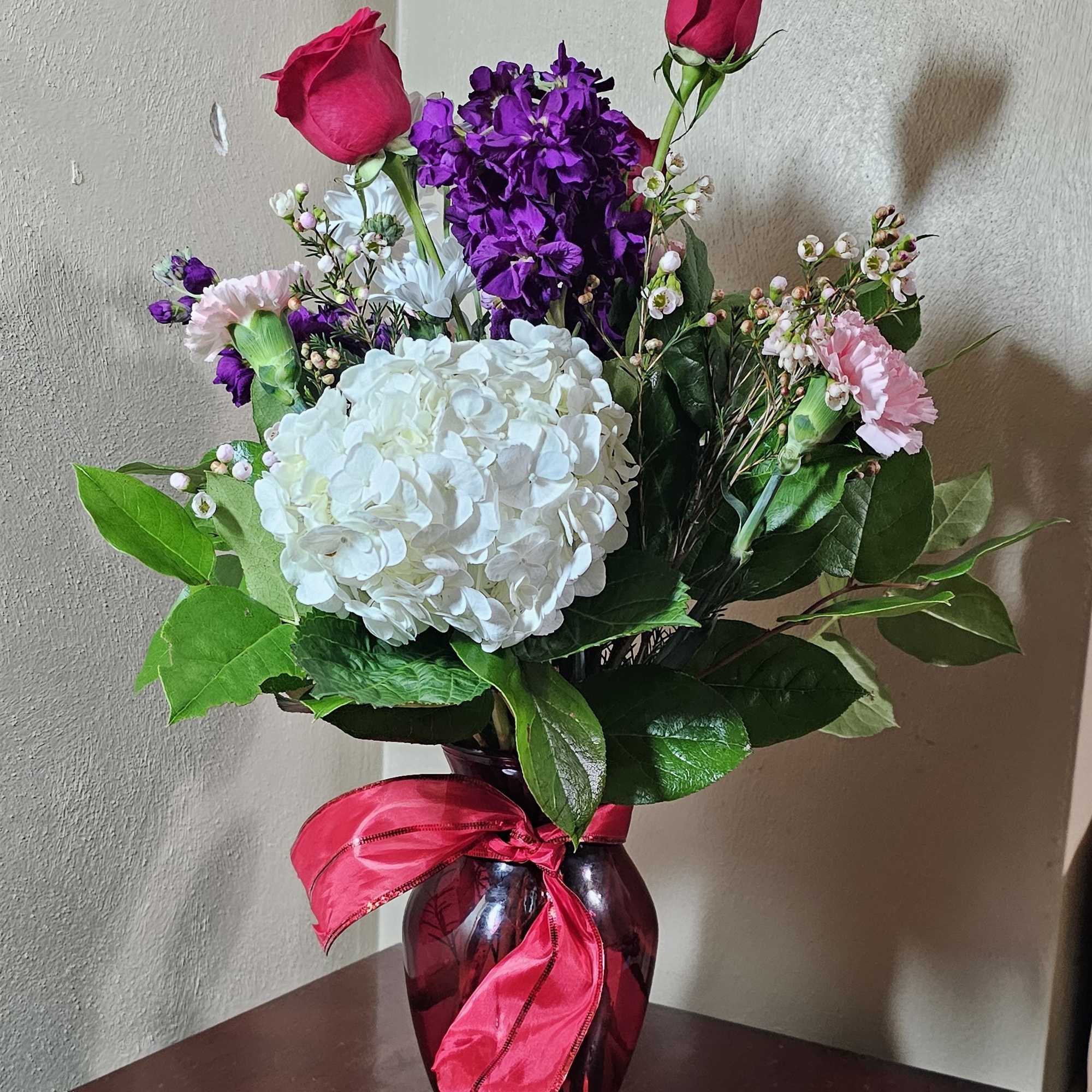 Red ruby vase filled with a variety of flowers representing Valentine&#039;s Days