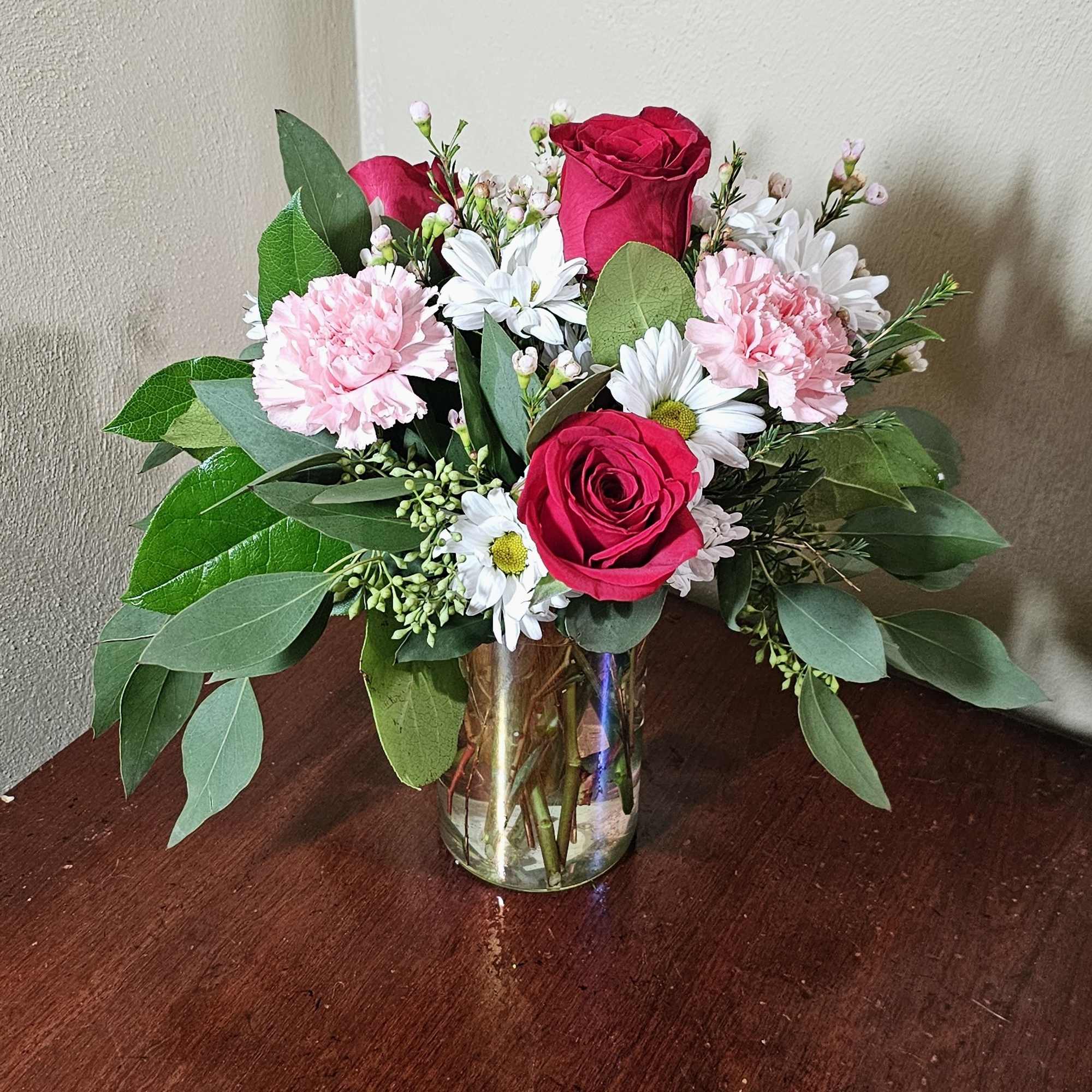 Iridescent cylinder vase with a bouquet of roses, carnations, and daisies. 