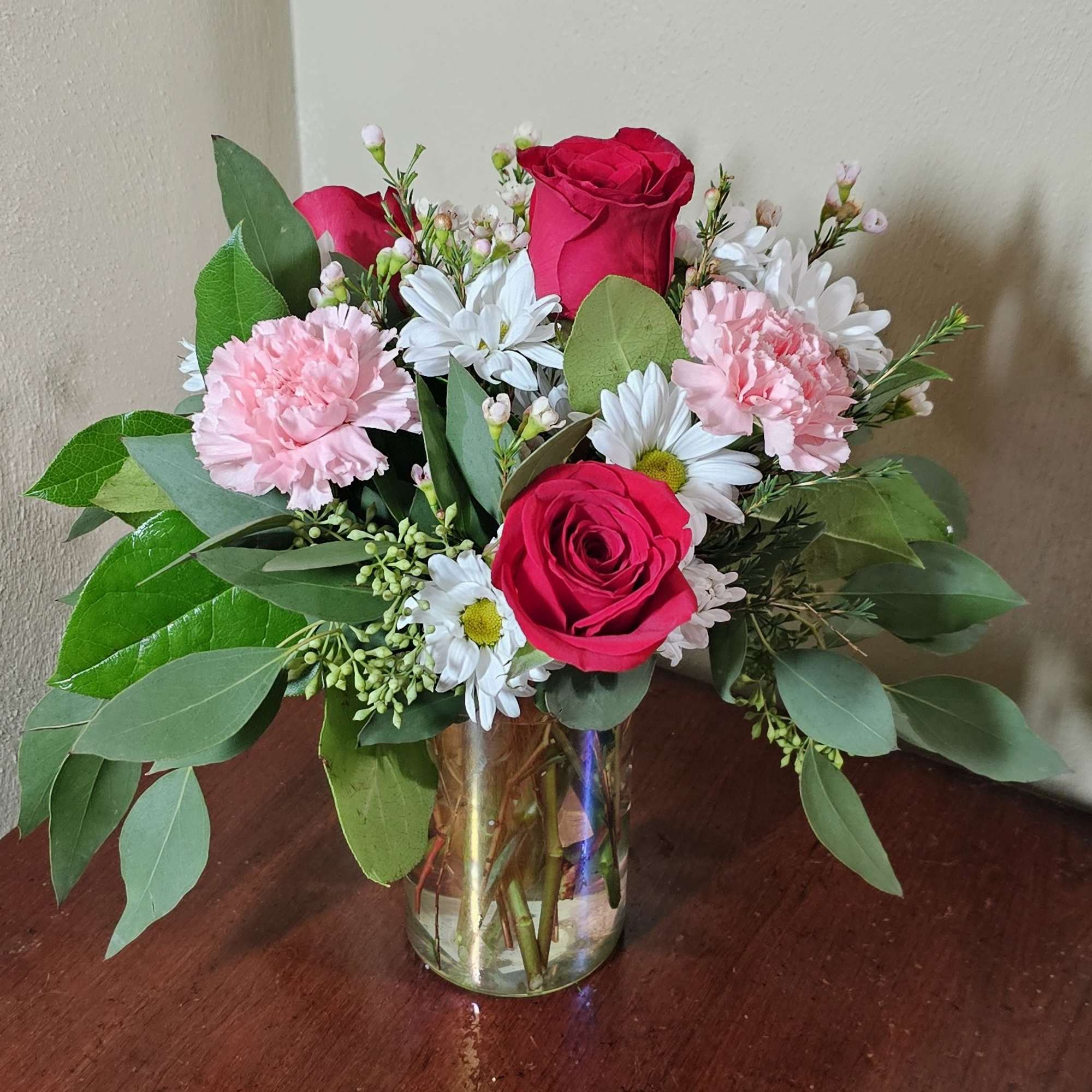 Iridescent cylinder vase with a bouquet of roses, carnations, and daisies. 