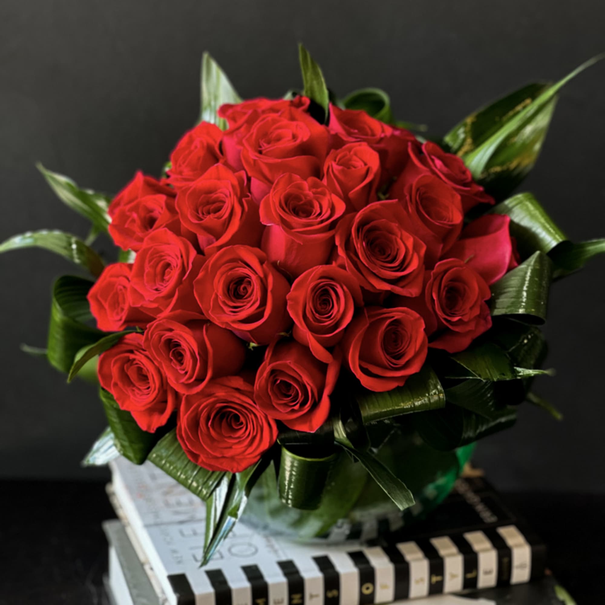 Modern design with 2 dozen red roses in clear vase with greenery