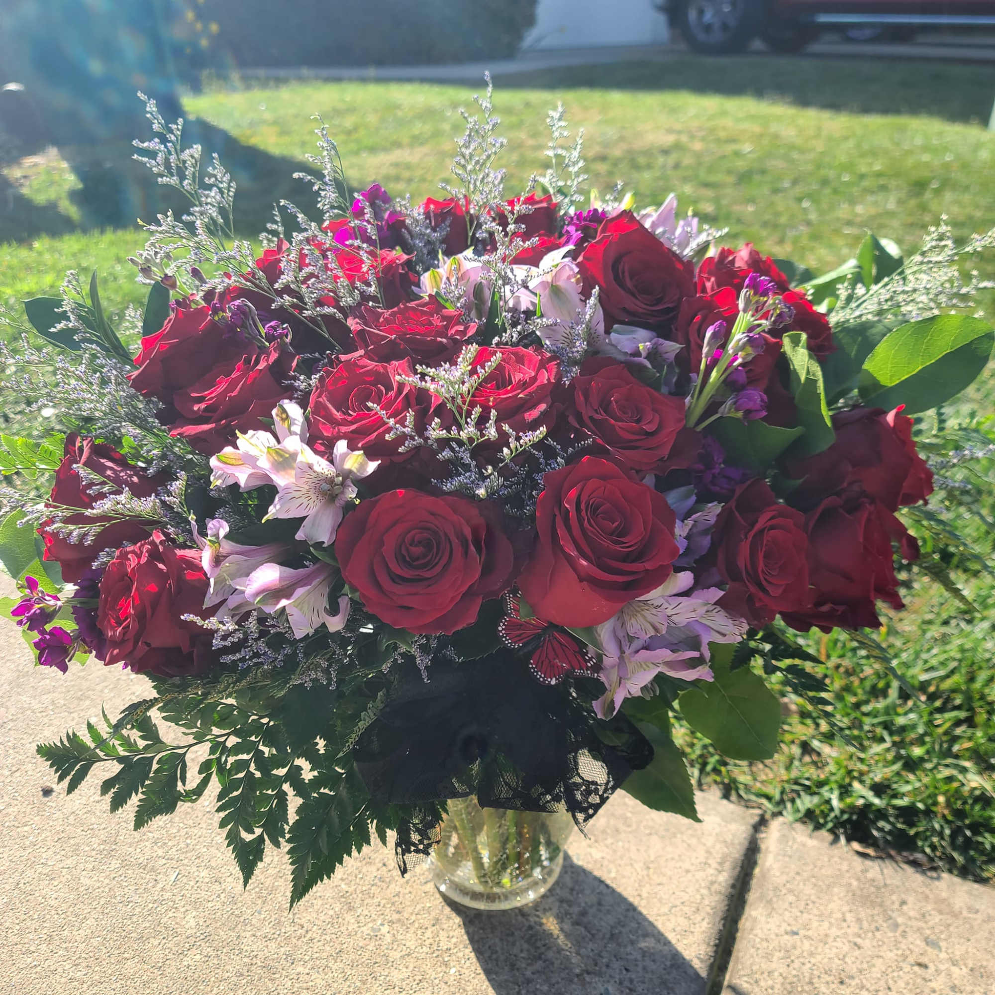long-stem red roses in a vase mixed with filler flowers, filler, and