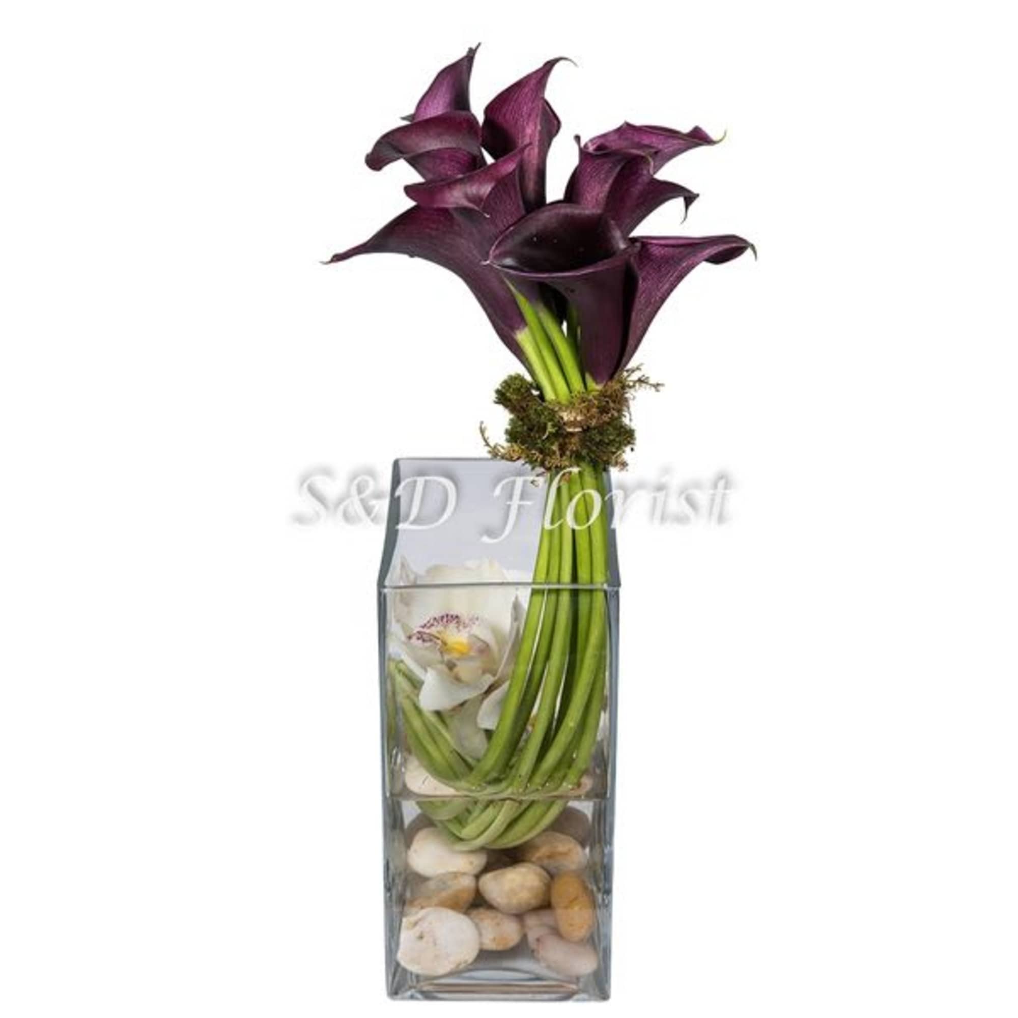 Purple calla lilies, cymbidium heads, river rocks with decorative green moss in