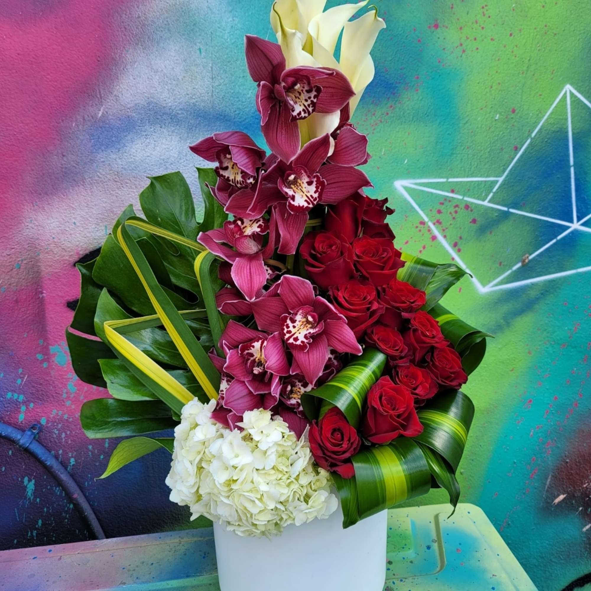 An arrangement in a vase, with roses, hydrangeas, Callas, cymbidium, and greenery. An arrangement in a vase, with roses, hydrangeas, Callas, cymbidium, and greenery.