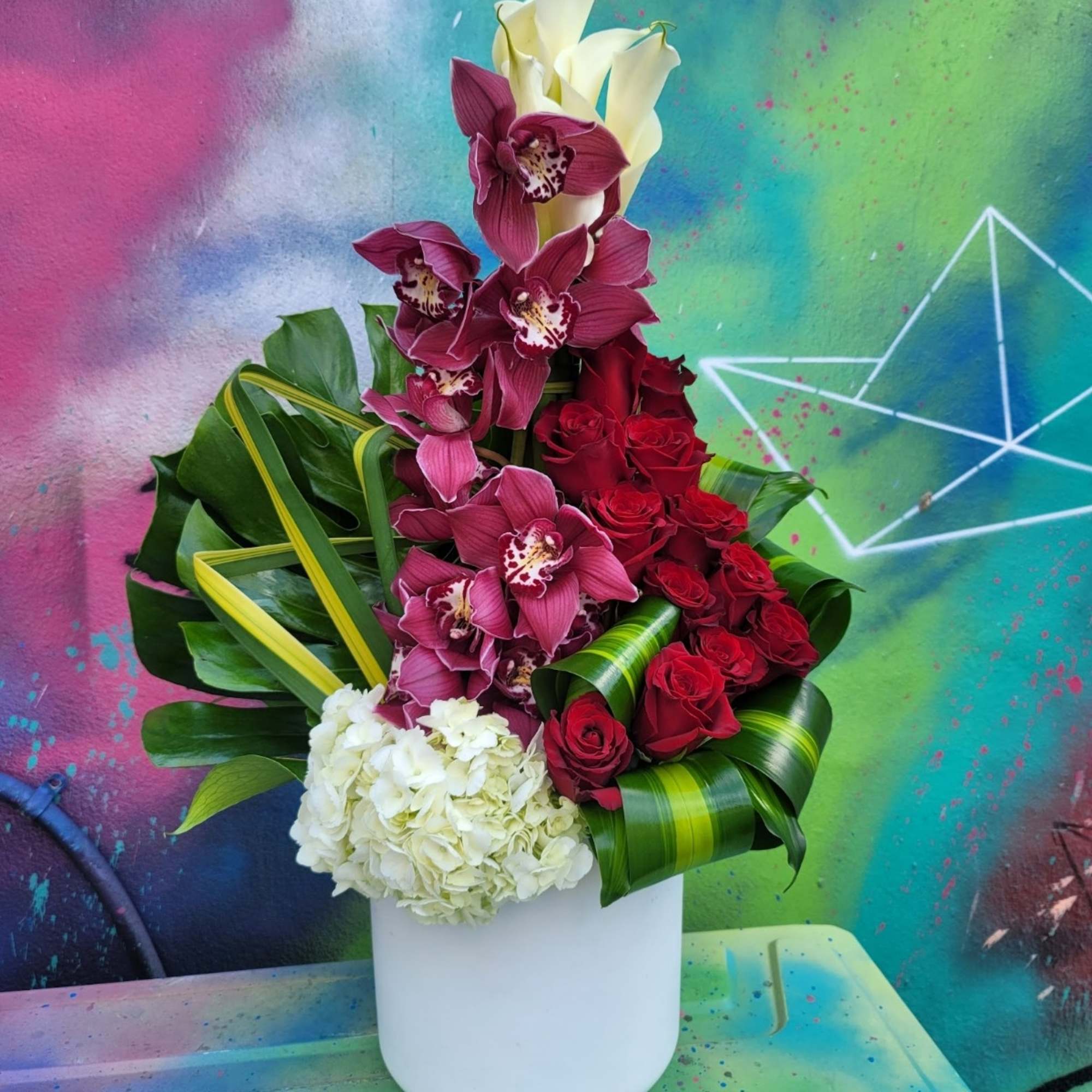 An arrangement in a vase, with roses, hydrangeas, Callas, cymbidium, and greenery. An arrangement in a vase, with roses, hydrangeas, Callas, cymbidium, and greenery.