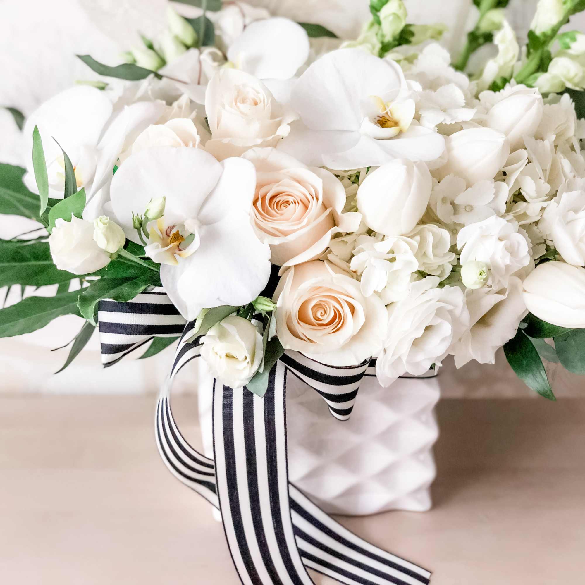 A pleasing combination of white orchids, white roses, white tulips, white hyndrangea