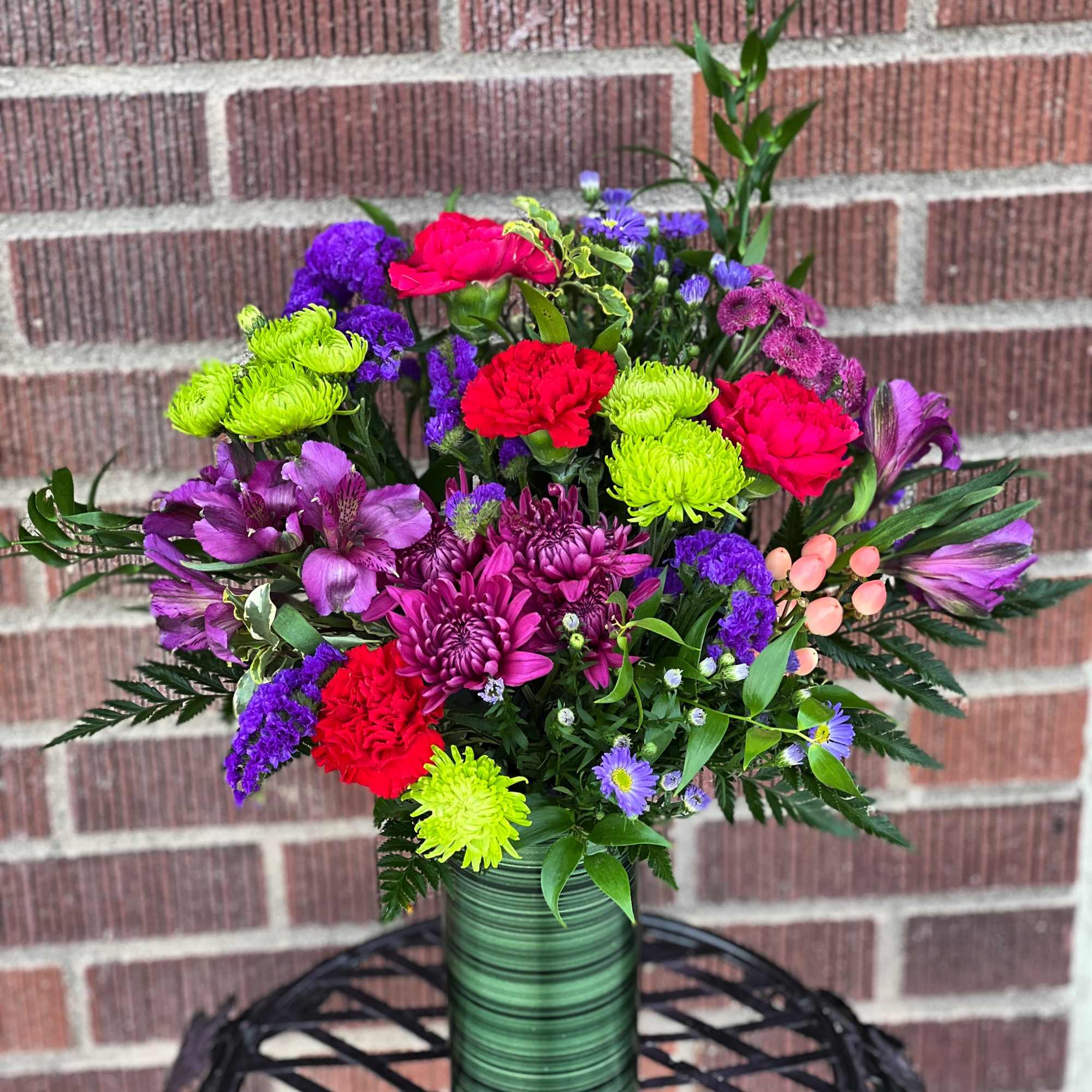 Rich and radiant, this vivid mix of jewel-toned blooms is wrapped with Rich and radiant, this vivid mix of jewel-toned blooms is wrapped with