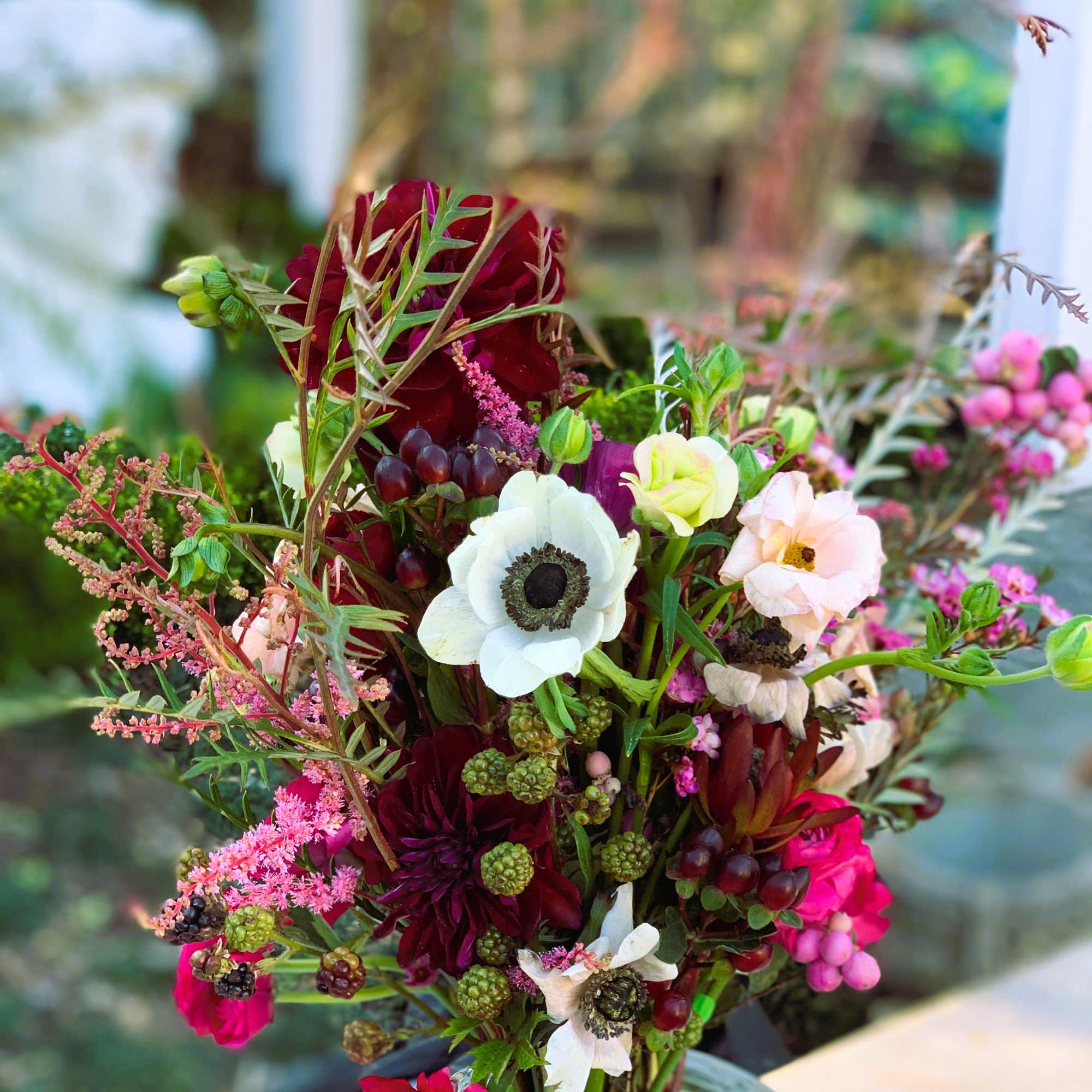 This wild and romantic bouquet of red shades and bold foliage is