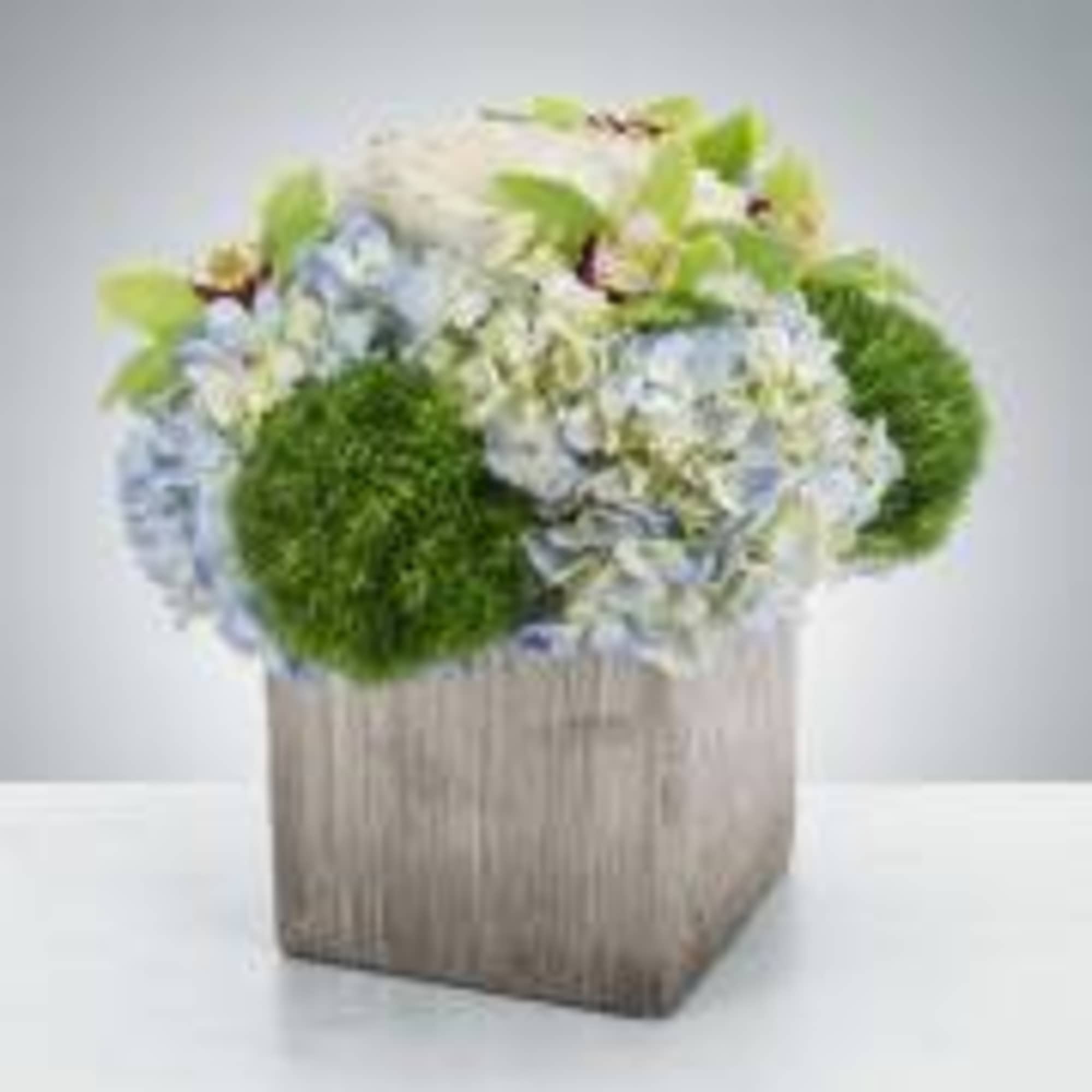 A blue and green arrangement in a stylish silver or white vase