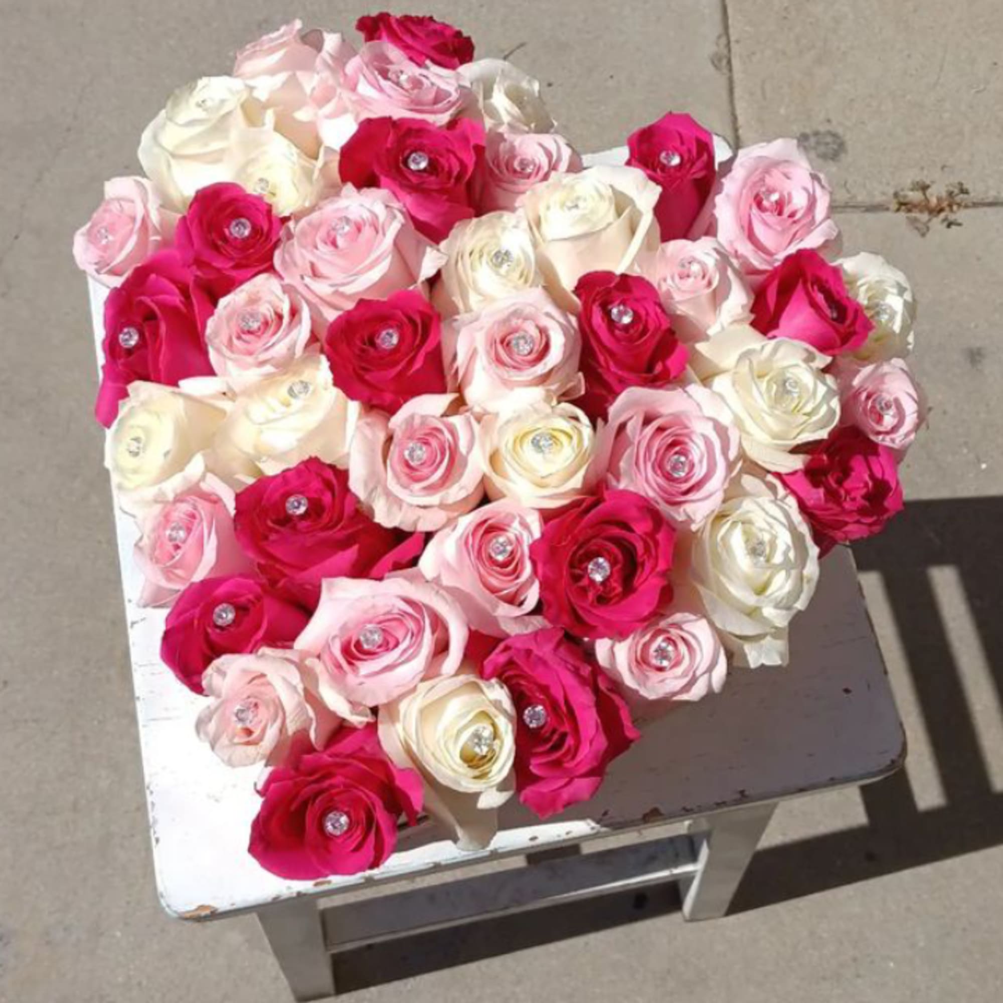 A heart shape box Bursting with 24 pink and white roses.

shade of