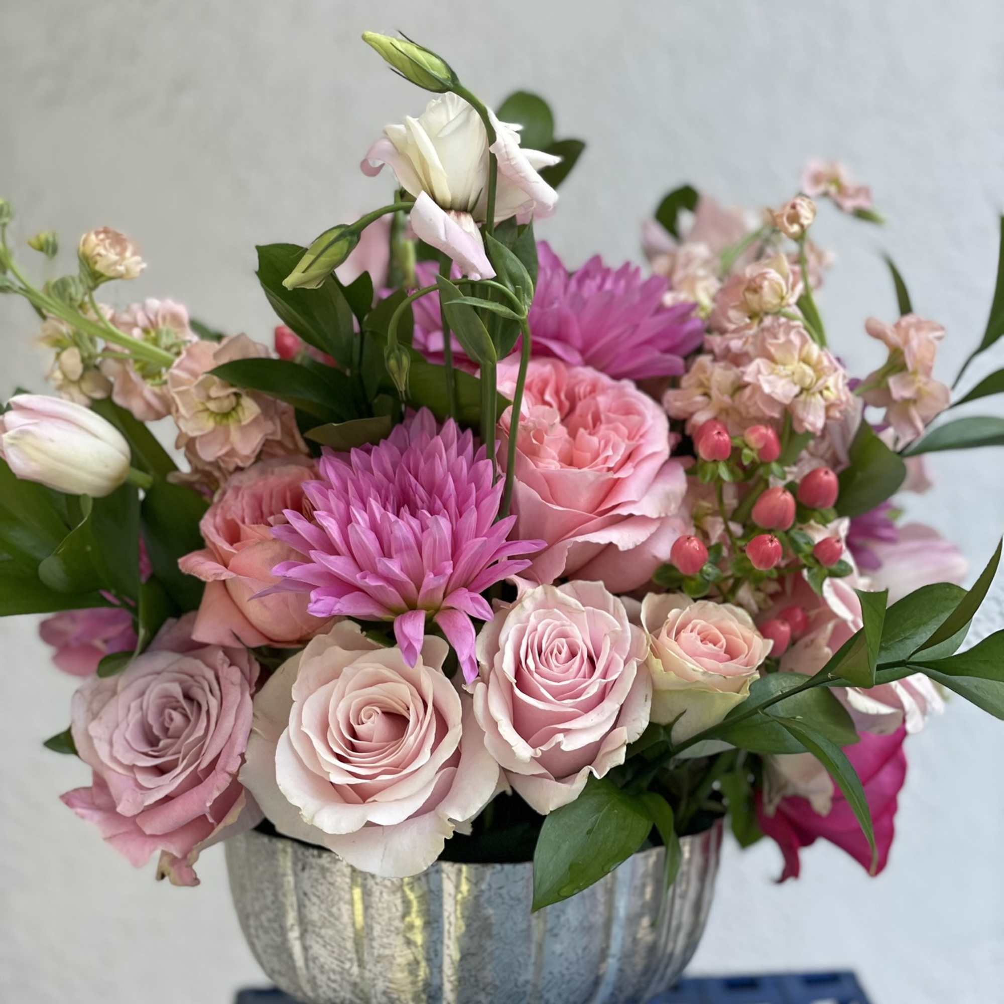 This arrangement bursts out of its container with pink tones from hot