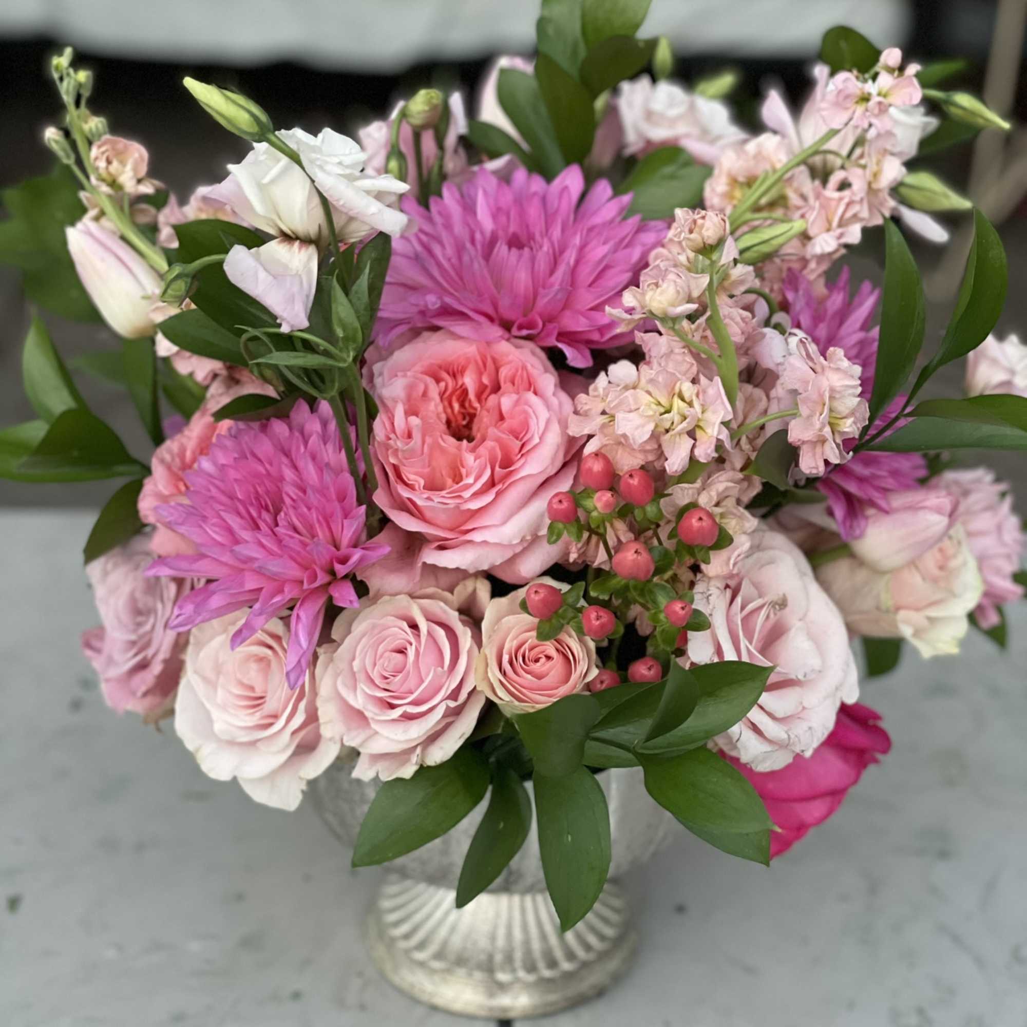 This arrangement bursts out of its container with pink tones from hot
