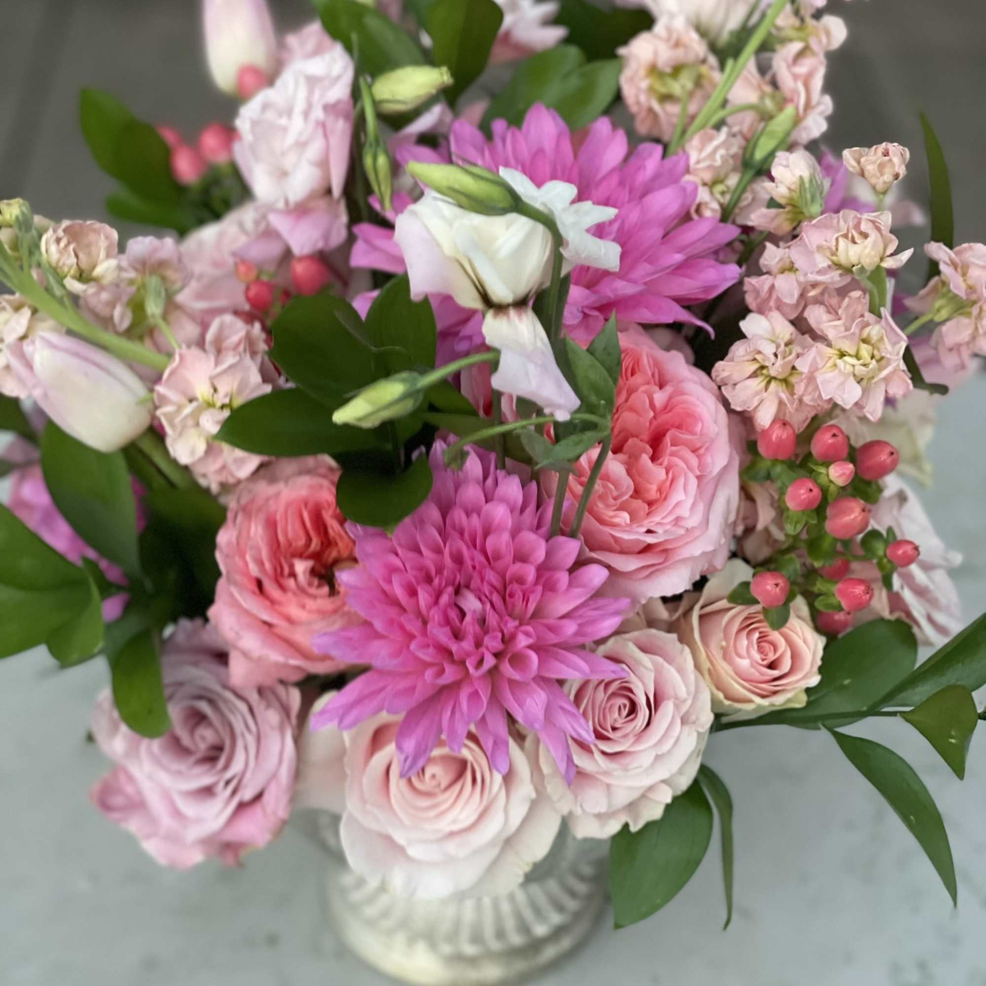 This arrangement bursts out of its container with pink tones from hot