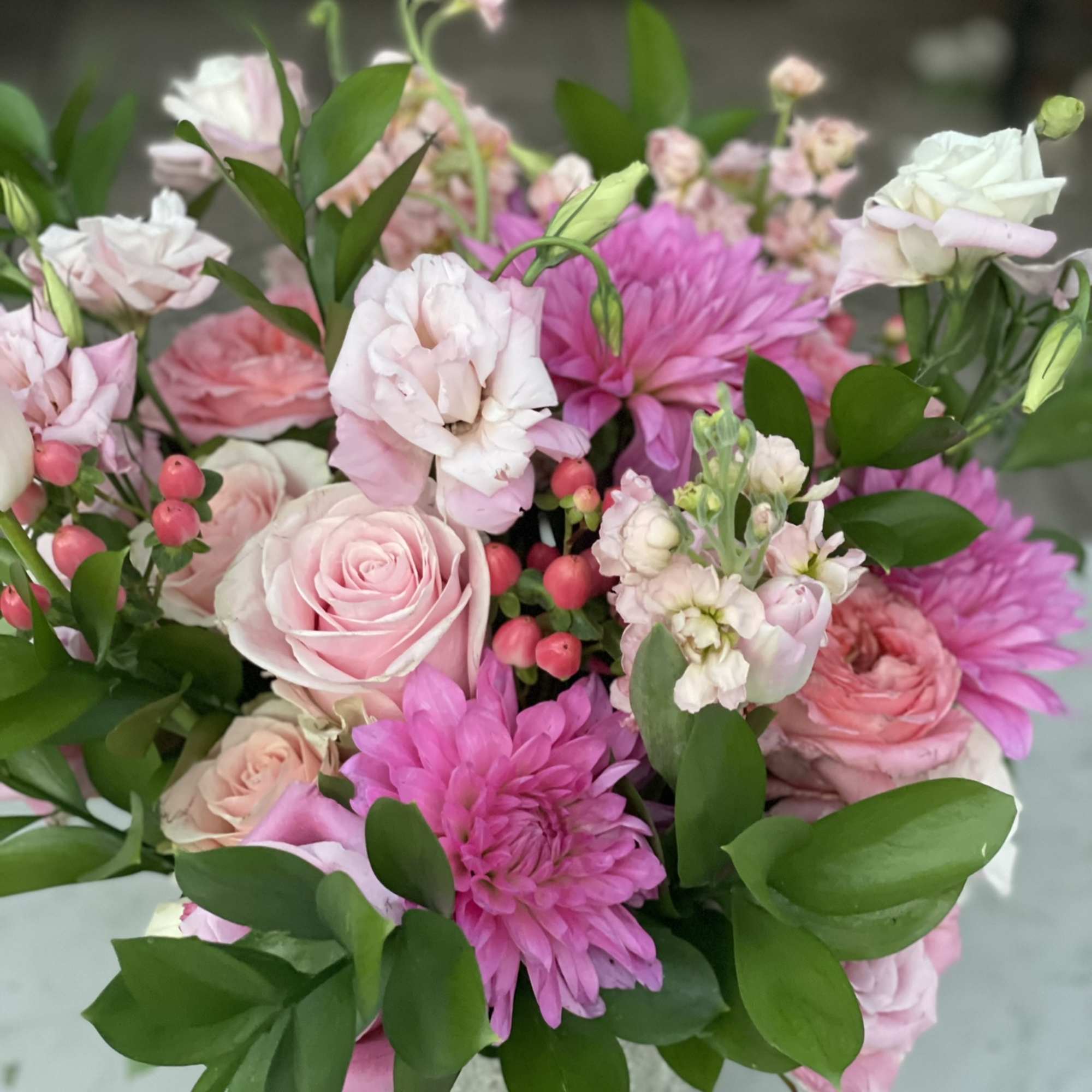 This arrangement bursts out of its container with pink tones from hot