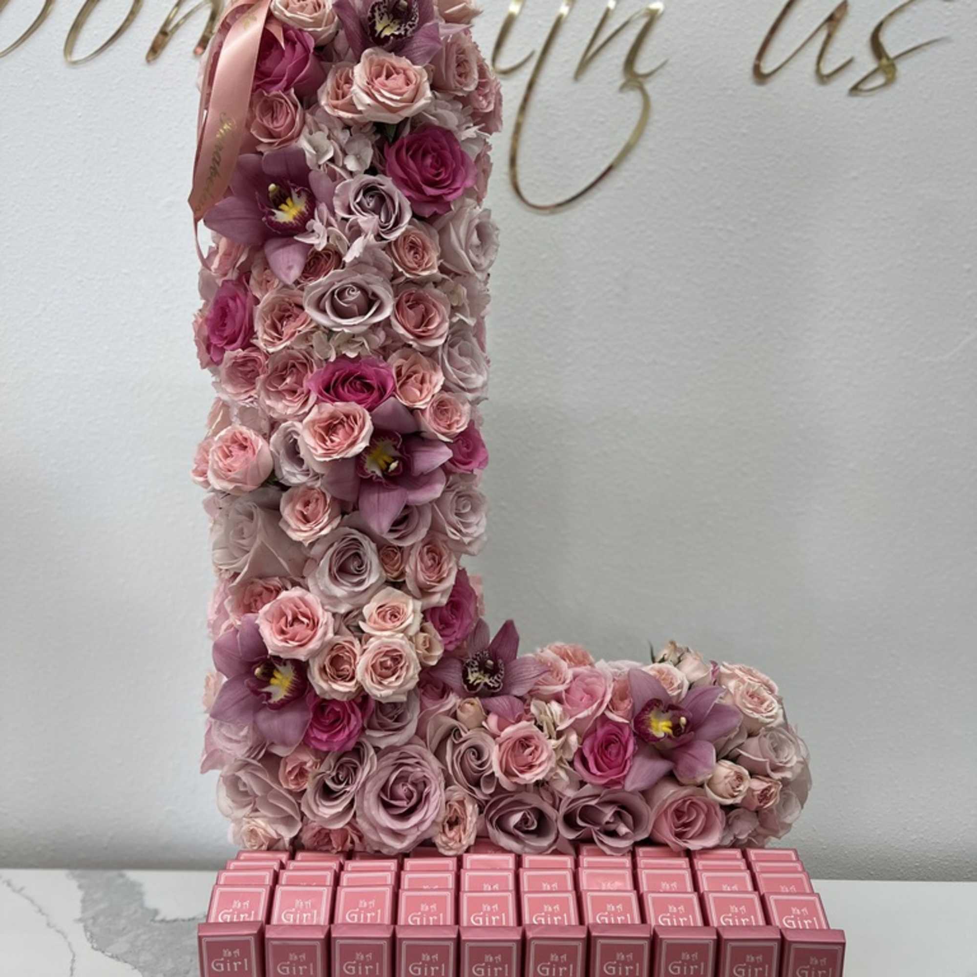 The fresh florals are carefully arranged in the shape of the letter