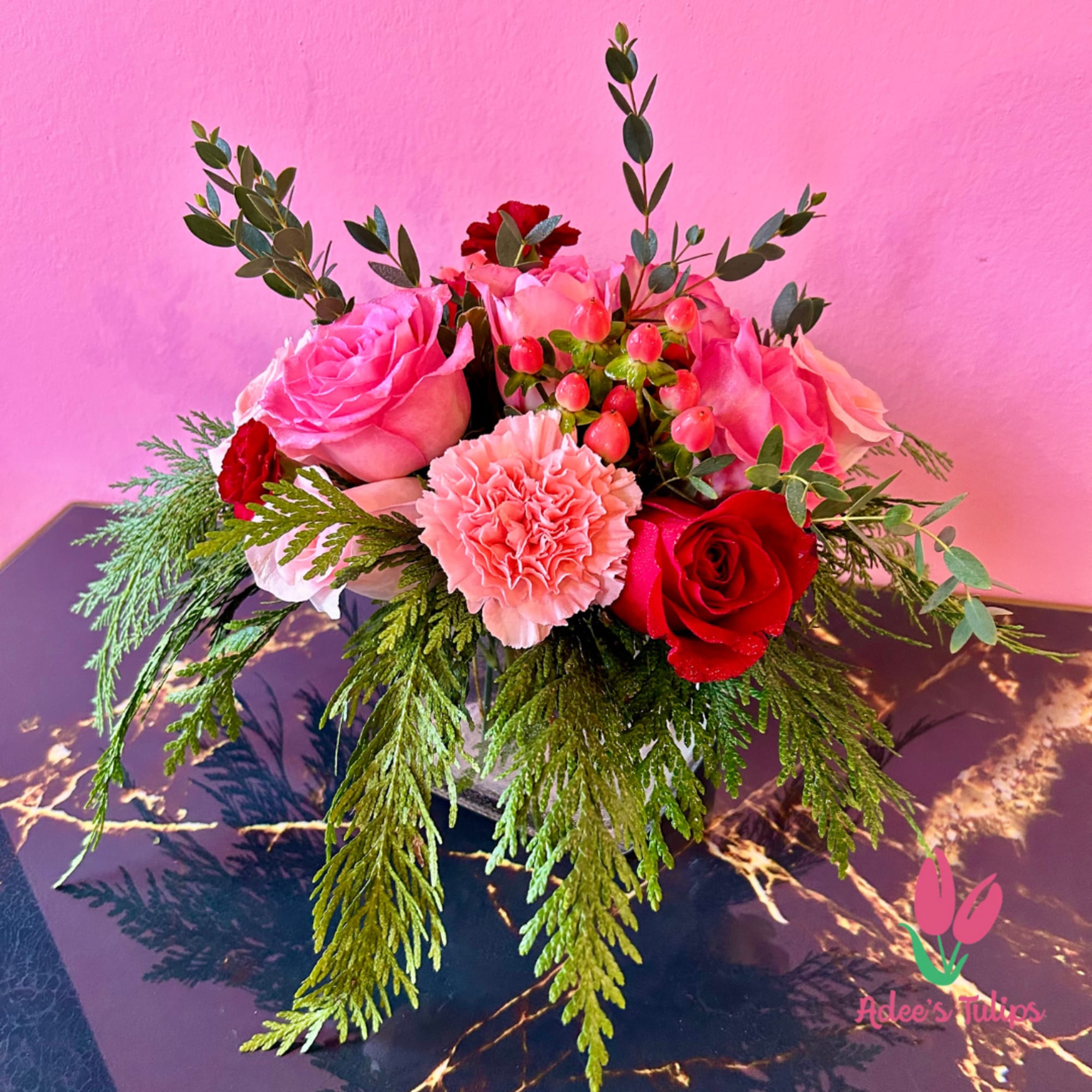 A beautiful vase arrangement of pink and red blooms, paired with eucalyptus