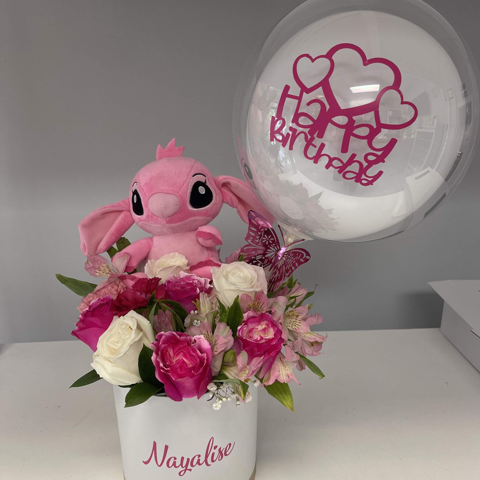 Pink and white roses topped with a pink butterfly and a personalized