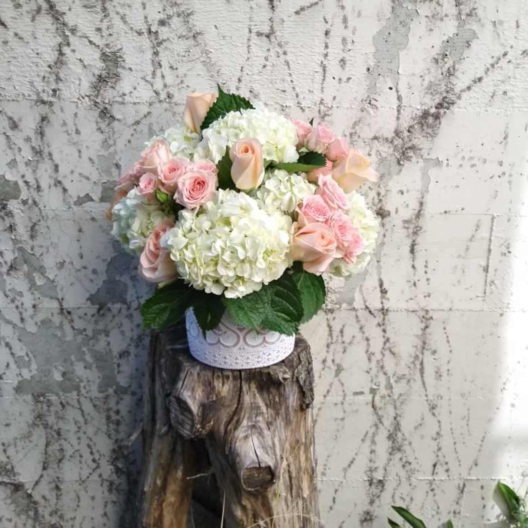 A well rounded array of white hydrangeas and pink roses, densely packed