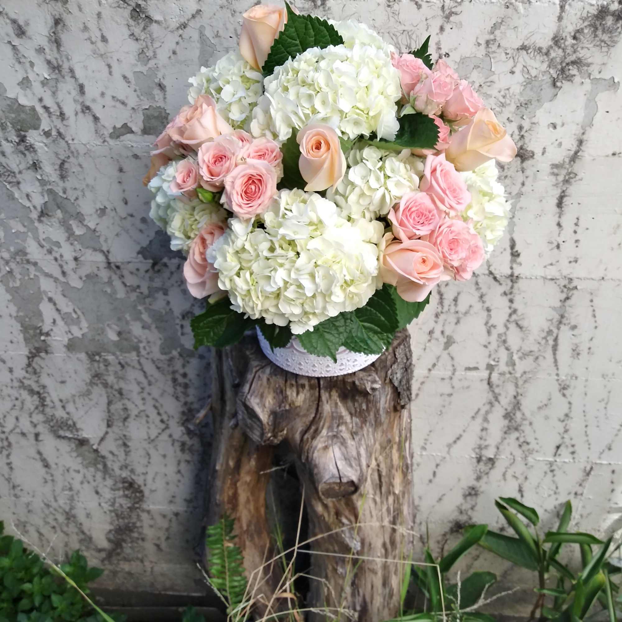 A well rounded array of white hydrangeas and pink roses, densely packed