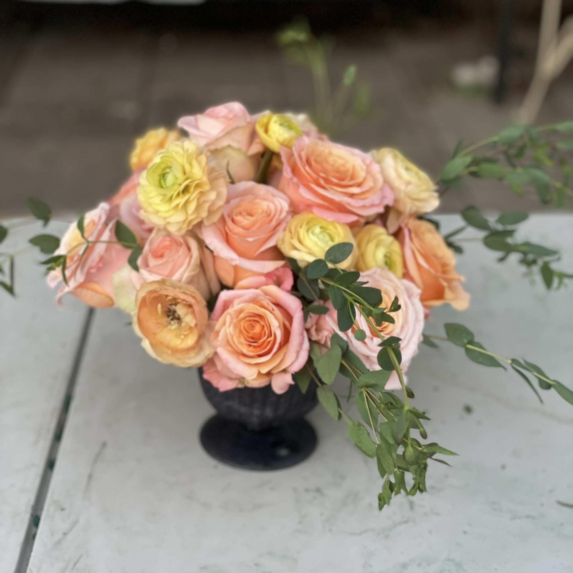 This compact arrangement of ranunculus, roses, and garden roses is full of