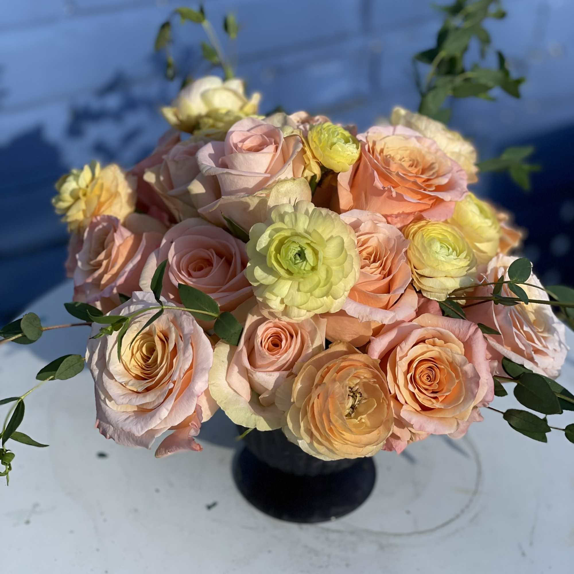 This compact arrangement of ranunculus, roses, and garden roses is full of