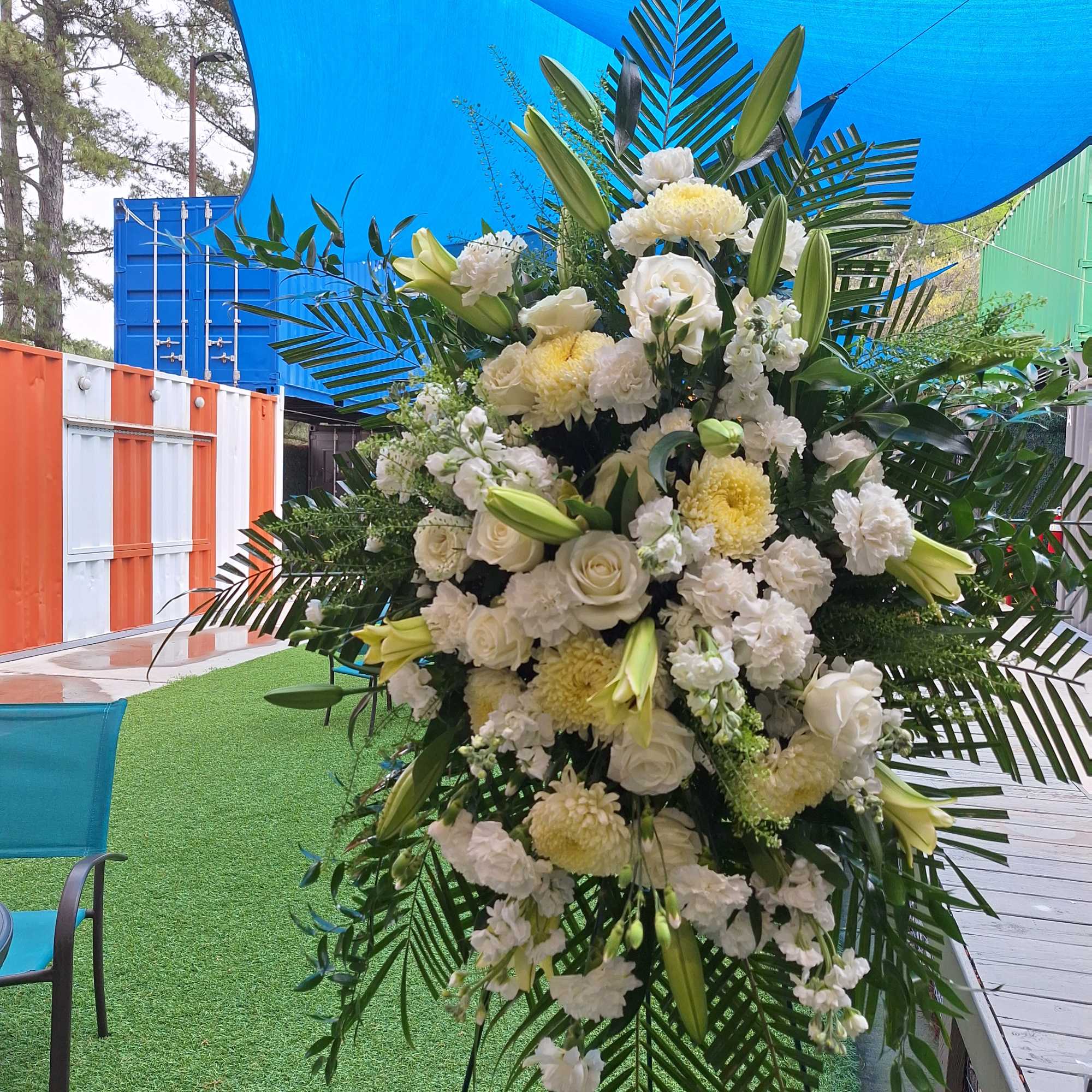 A standing spray with varied white flowers, greenery in tasteful design.  A standing spray with varied white flowers, greenery in tasteful design.