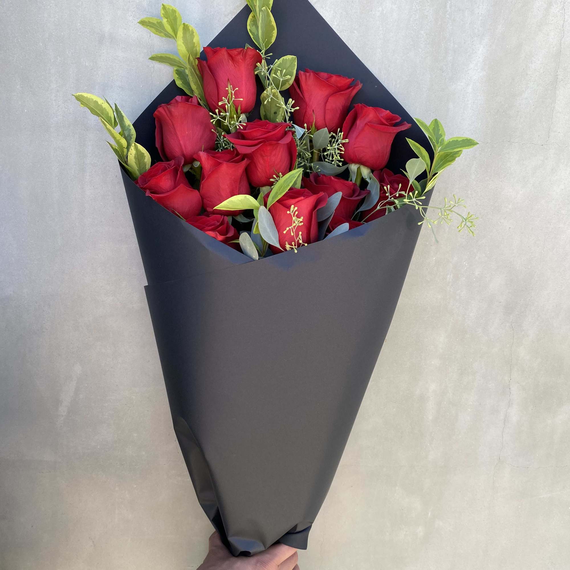 Lovely long stem red rose with greenery wrapped in our limited black