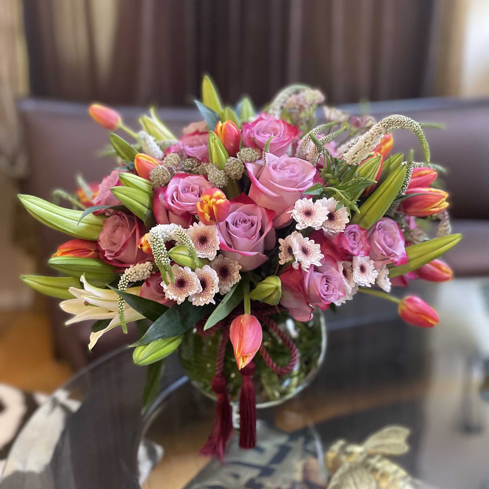 This lavish arrangement of lilies and roses is a captivating masterpiece that