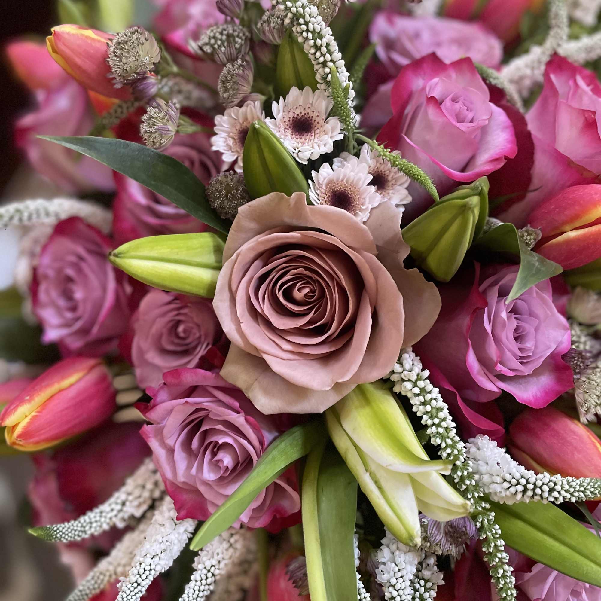 This lavish arrangement of lilies and roses is a captivating masterpiece that