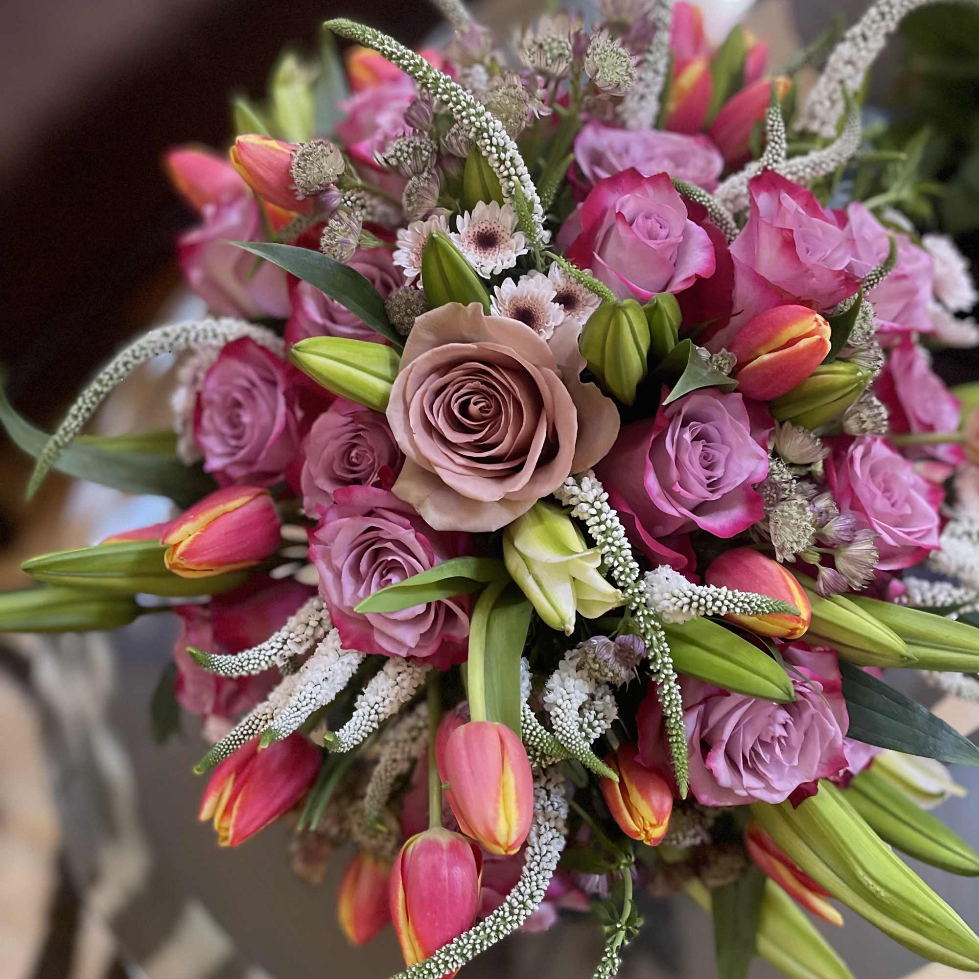 This lavish arrangement of lilies and roses is a captivating masterpiece that