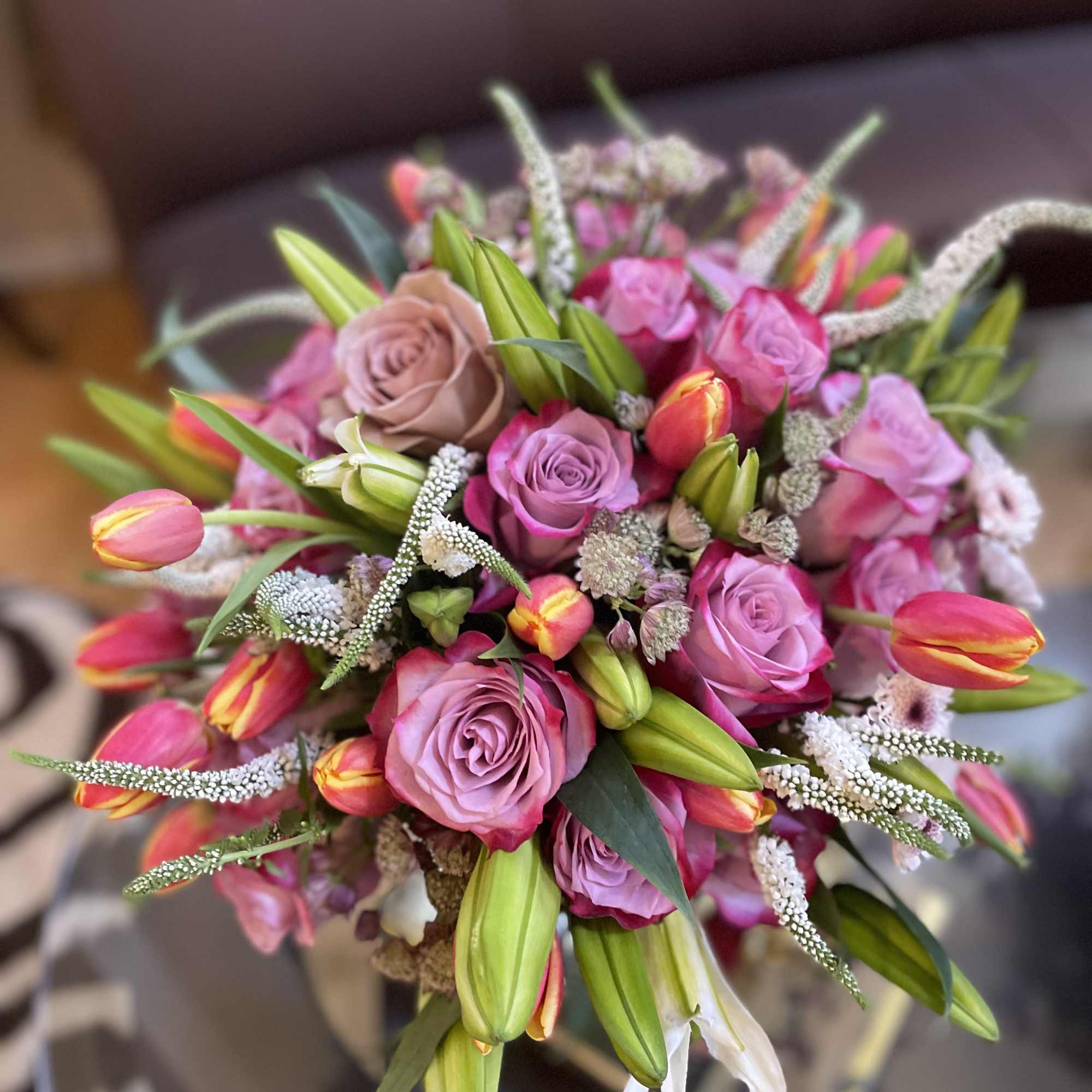 This lavish arrangement of lilies and roses is a captivating masterpiece that