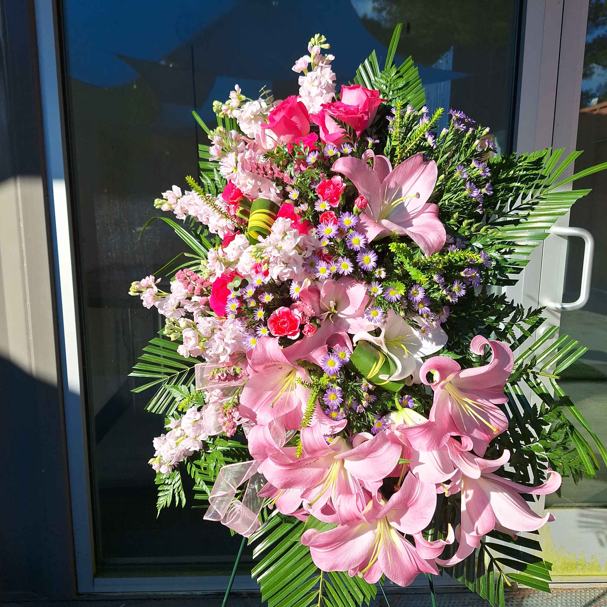 A tribute in pink with hot pink Roses, stock and Lilies arranged A tribute in pink with hot pink Roses, stock and Lilies arranged