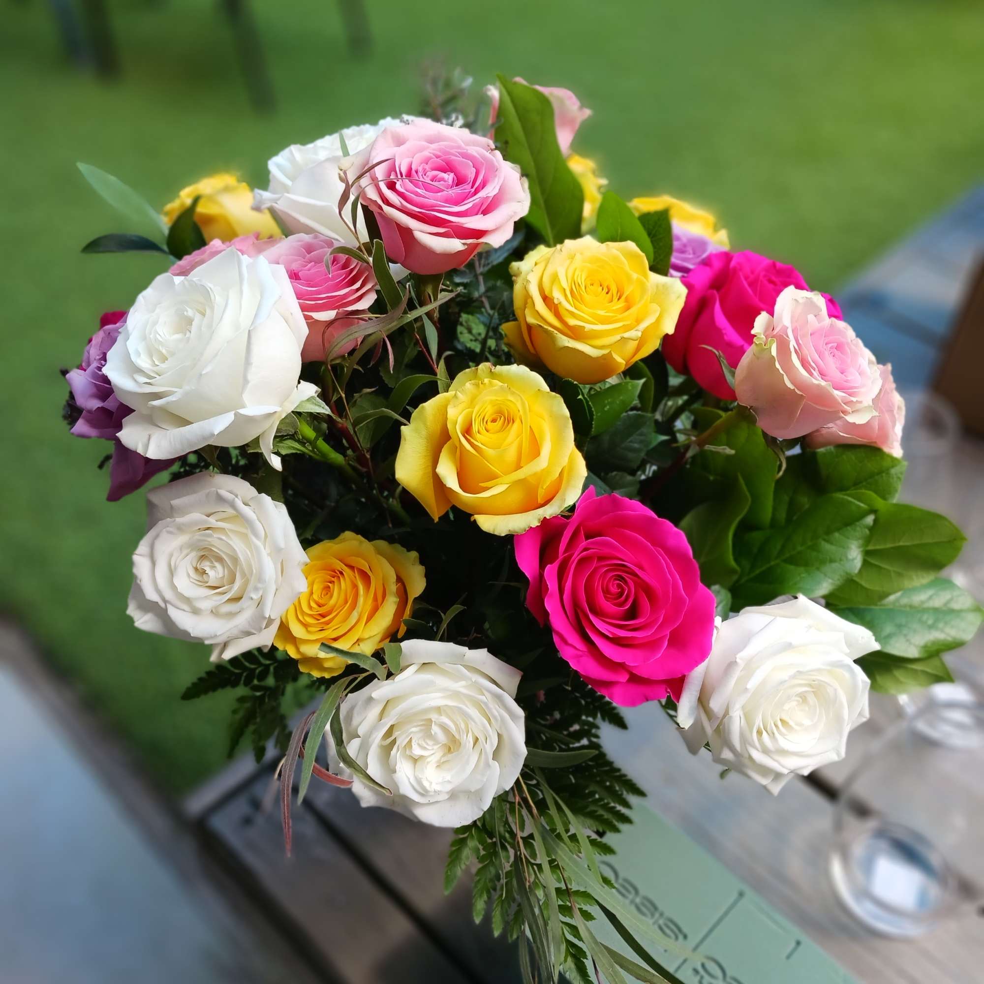 One dozen roses, assorted filler and greenery in a clear vase. One dozen roses, assorted filler and greenery in a clear vase.