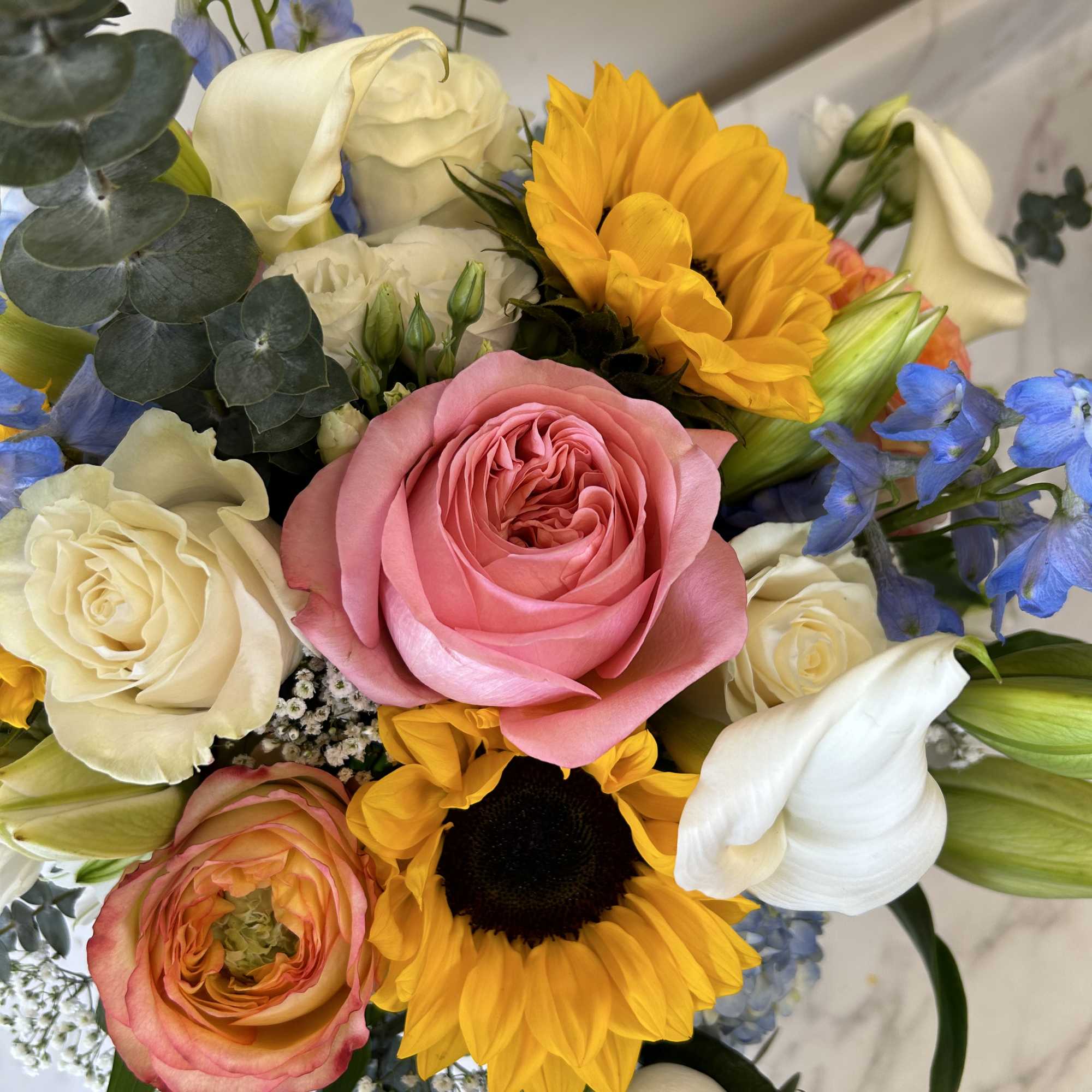 Mixed roses with sunflowers, delphinium and eucalyptus in a vase