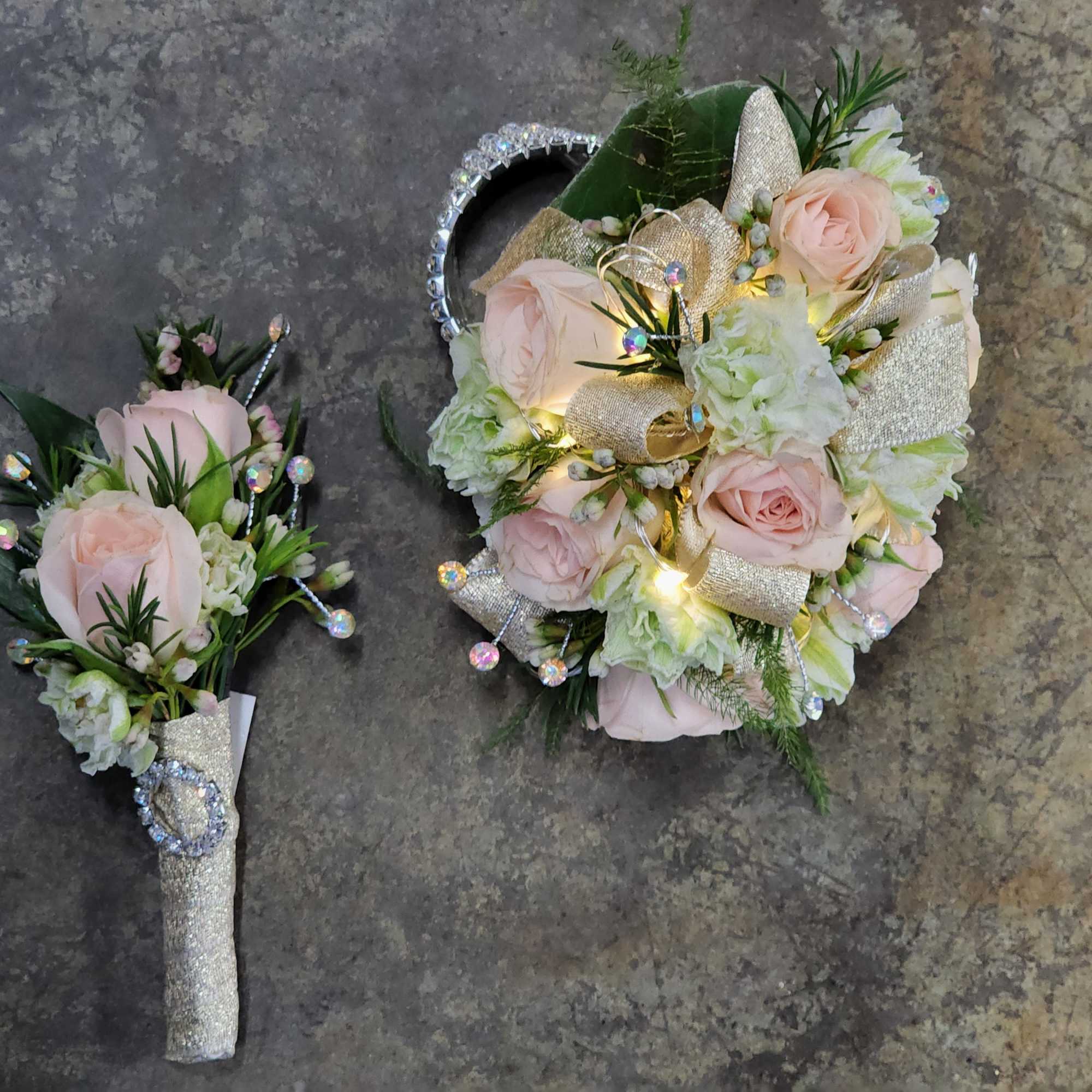 A wrist corsage and boutonniere set with light pink spray roses, white