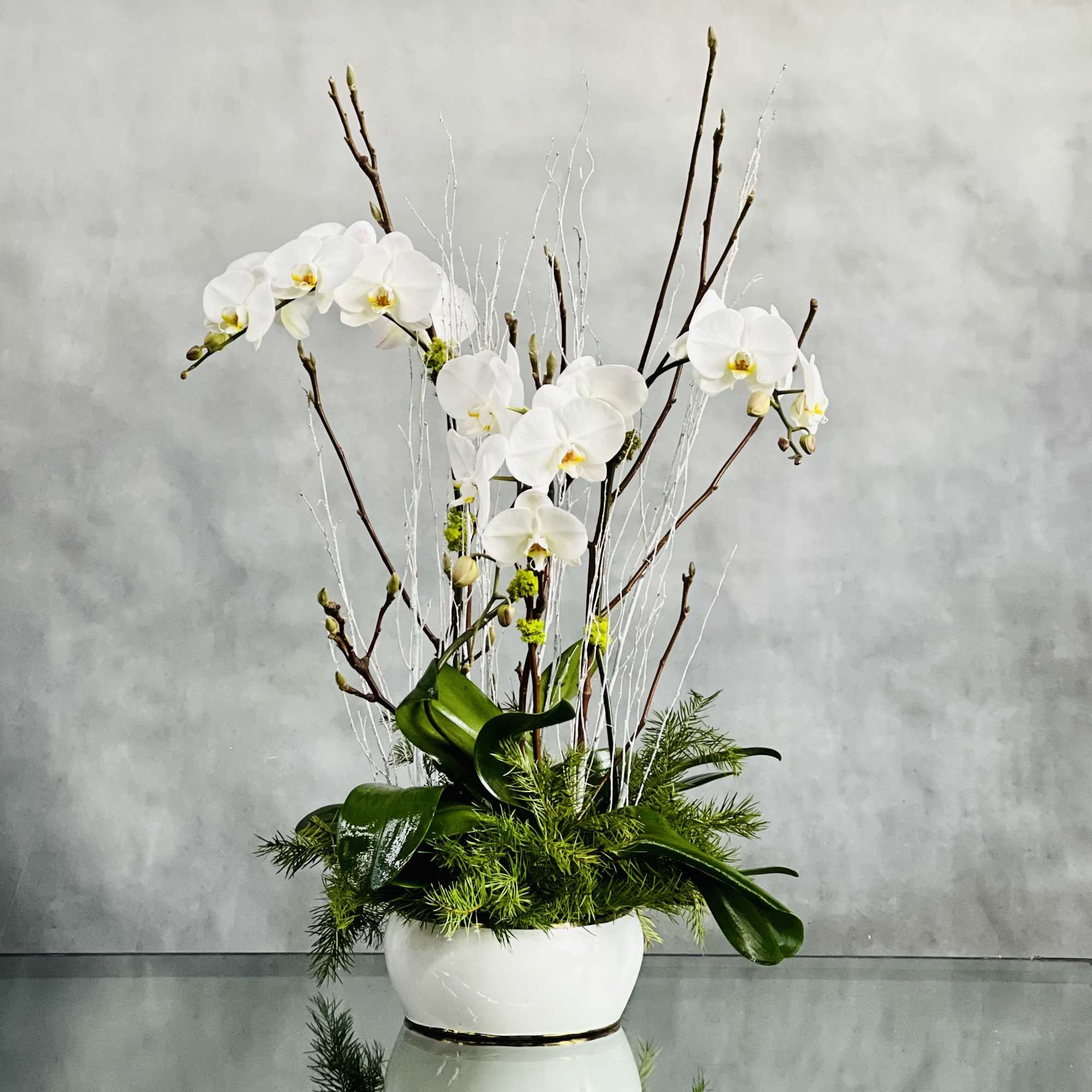 Three stemmed White Orchids grace this design with their soft blooms dancing