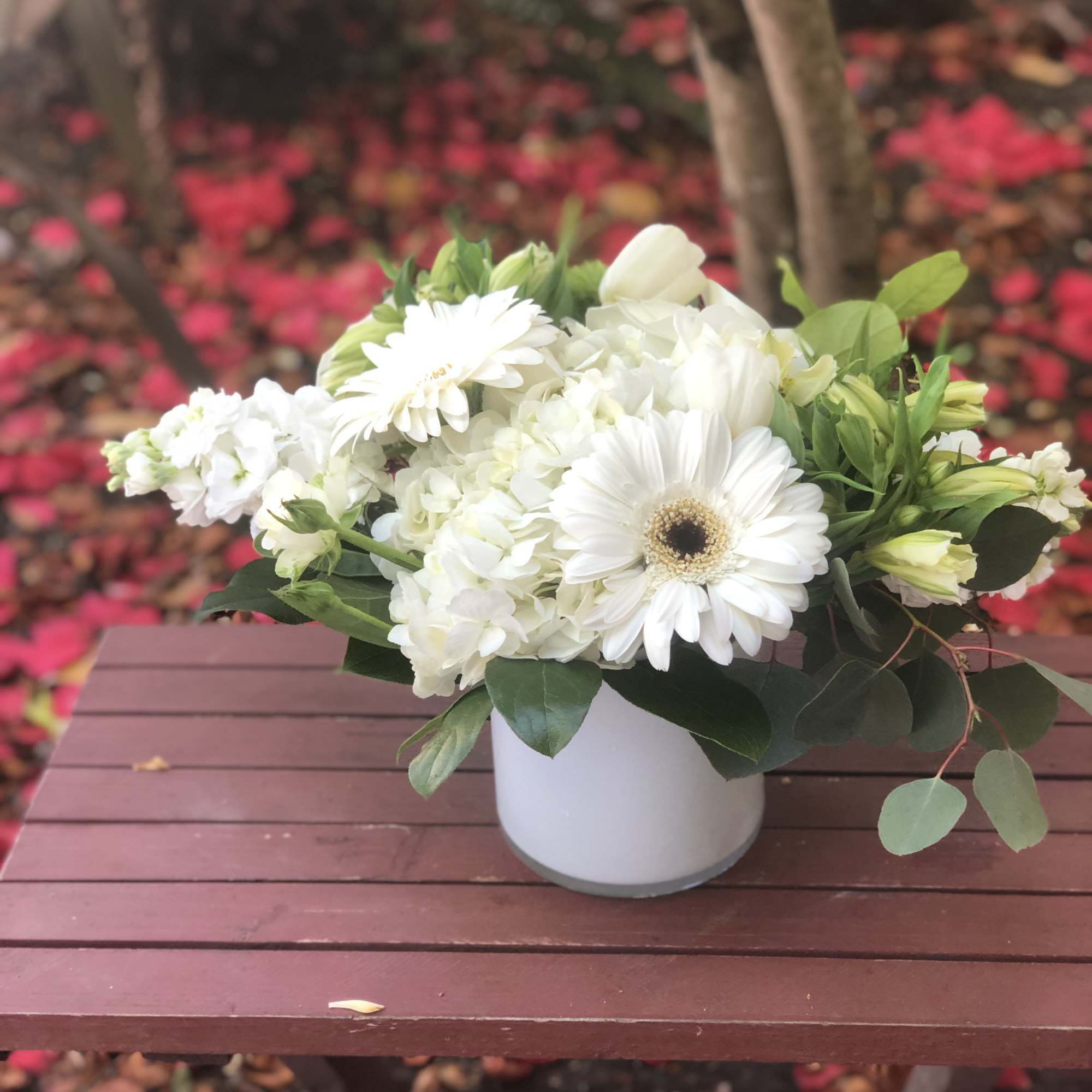 This arrangement contains gerbera daisies, roses, stock, and other seasonal blooms. APPROXIMATE