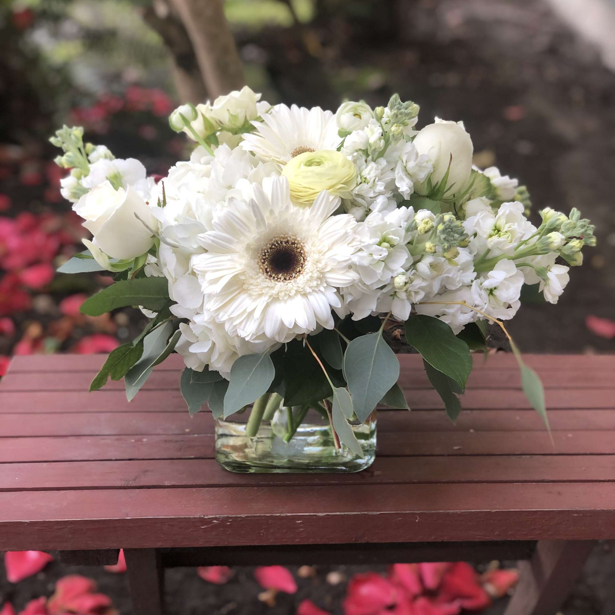 This arrangement contains gerbera daisies, roses, stock, and other seasonal blooms. APPROXIMATE