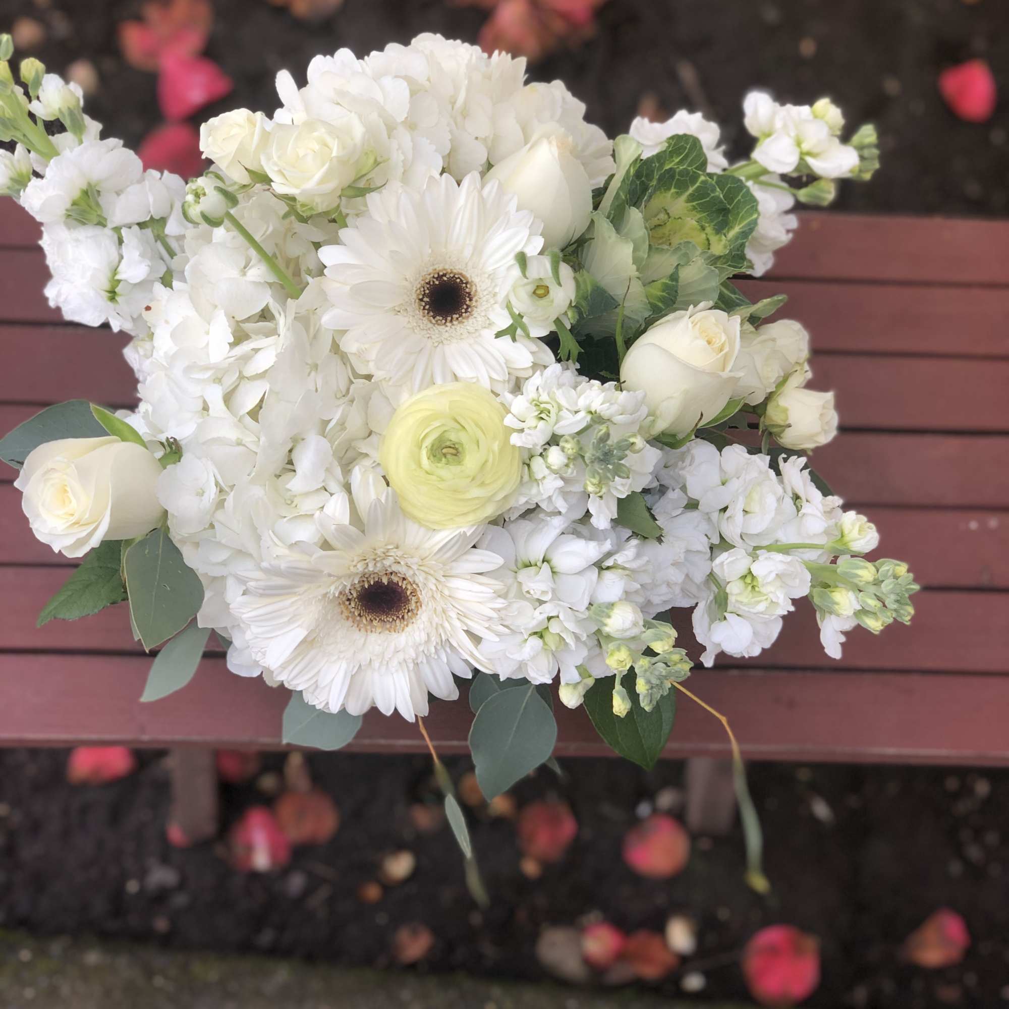 This arrangement contains gerbera daisies, roses, stock, and other seasonal blooms. APPROXIMATE