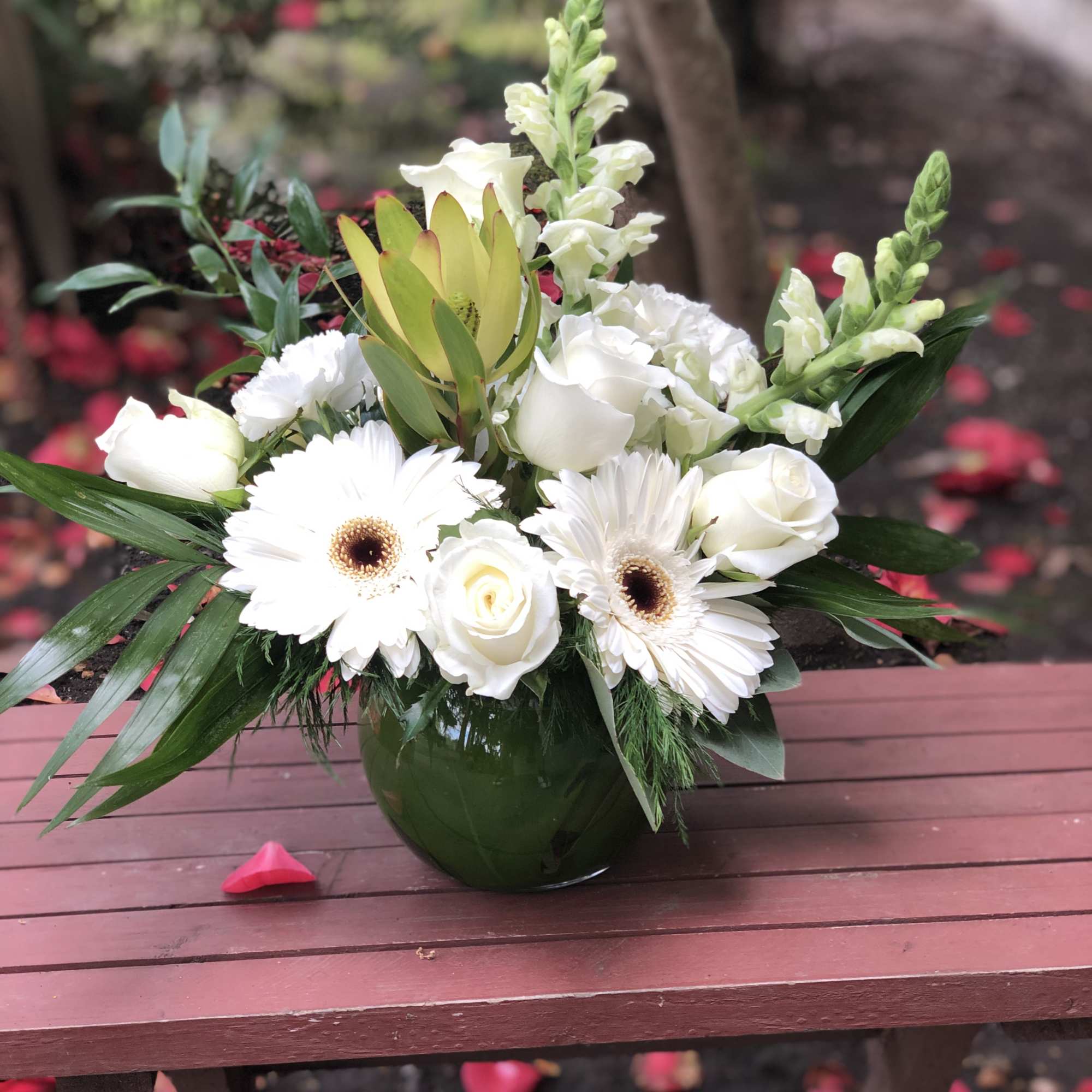 This arrangement contains gerbera daisies, roses, stock, and other seasonal blooms. APPROXIMATE