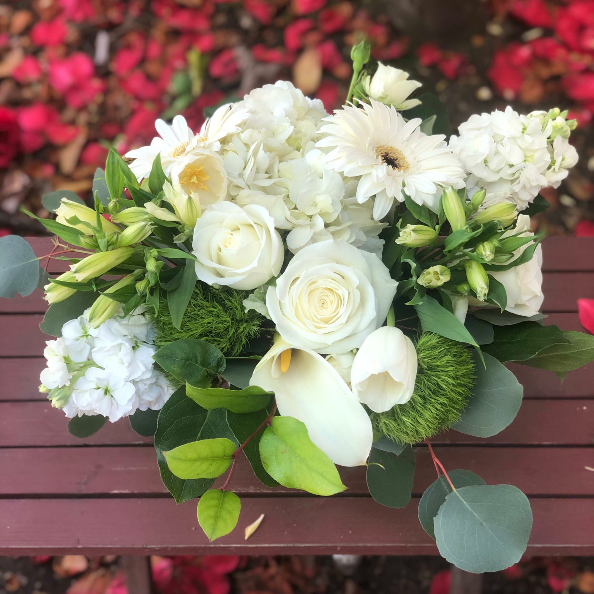 This arrangement contains gerbera daisies, roses, stock, and other seasonal blooms. APPROXIMATE