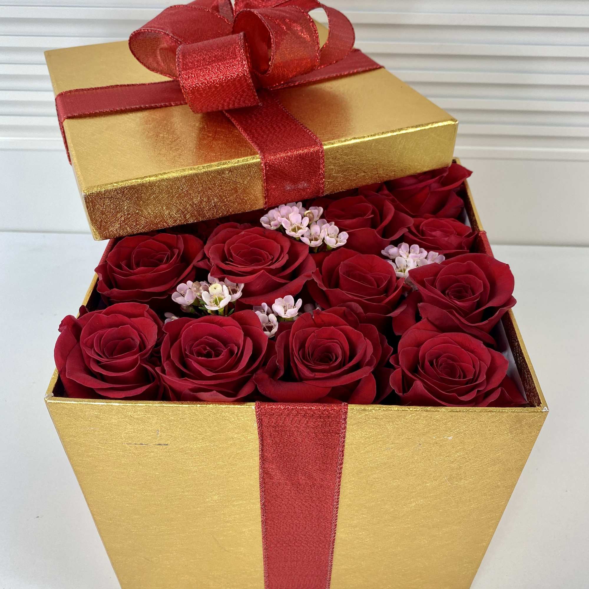 Tall golden gift box filled with 16 fresh red roses.