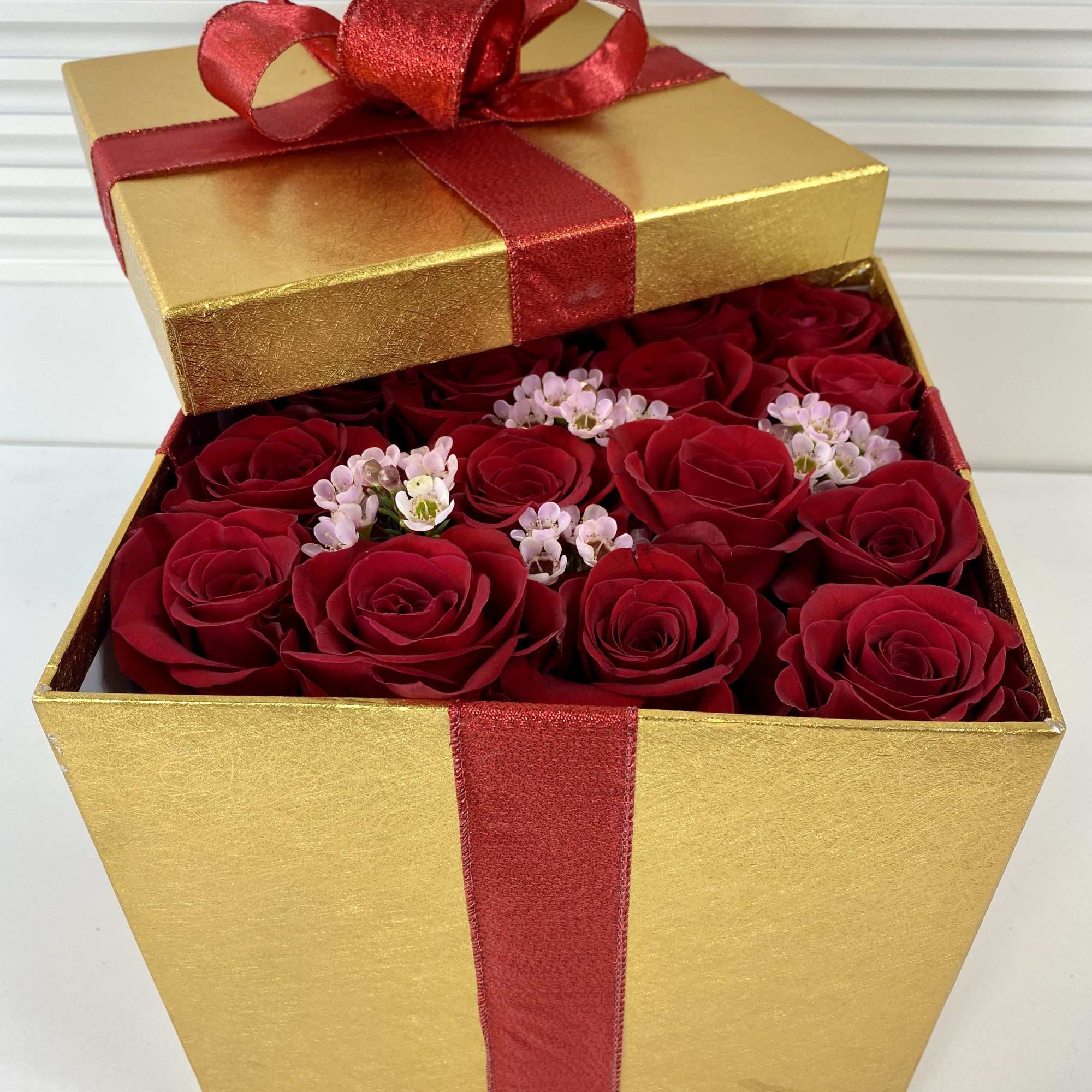 Tall golden gift box filled with 16 fresh red roses.