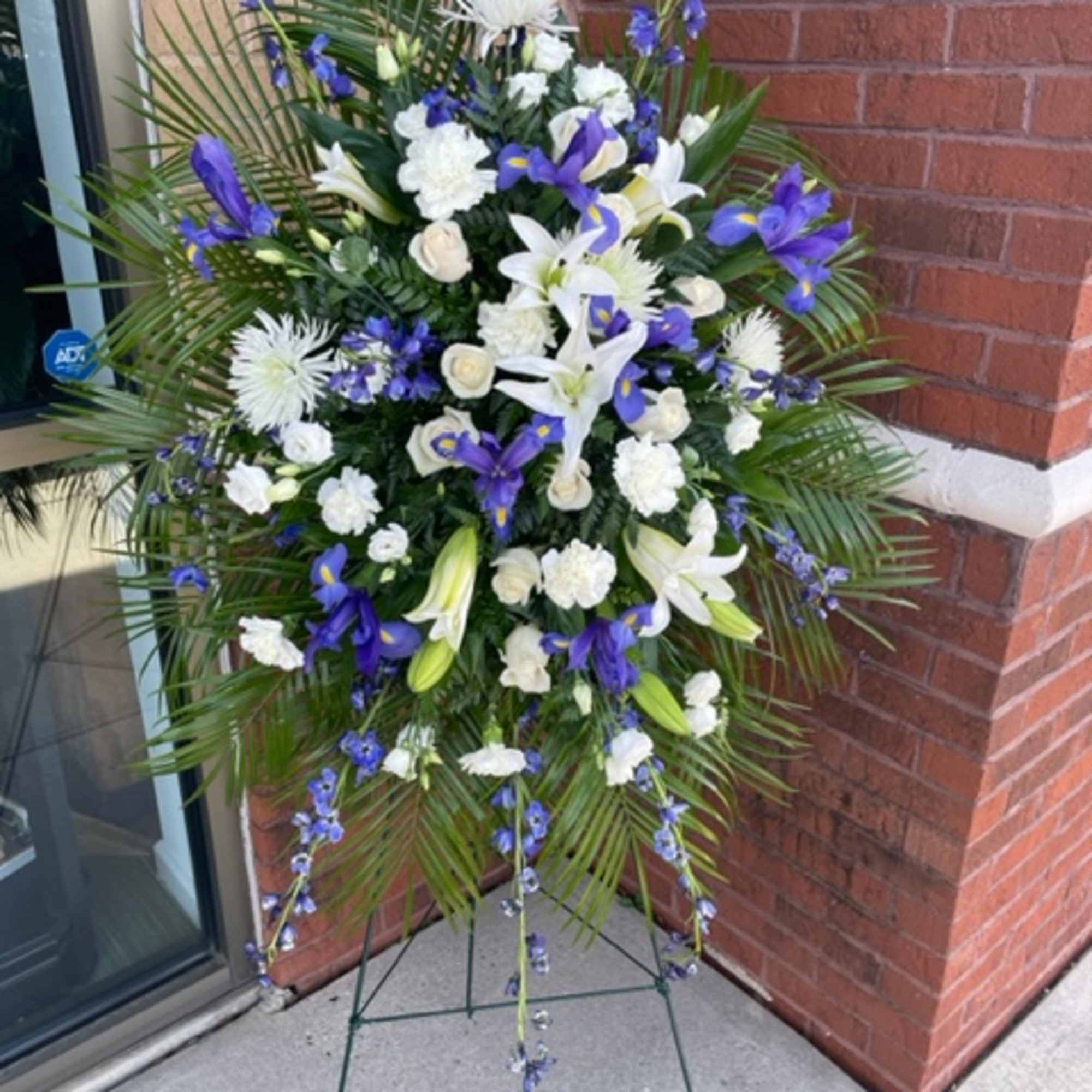 Standing spray with blue delphinium, white lilies, white/cream roses, white carnations, and Standing spray with blue delphinium, white lilies, white/cream roses, white carnations, and