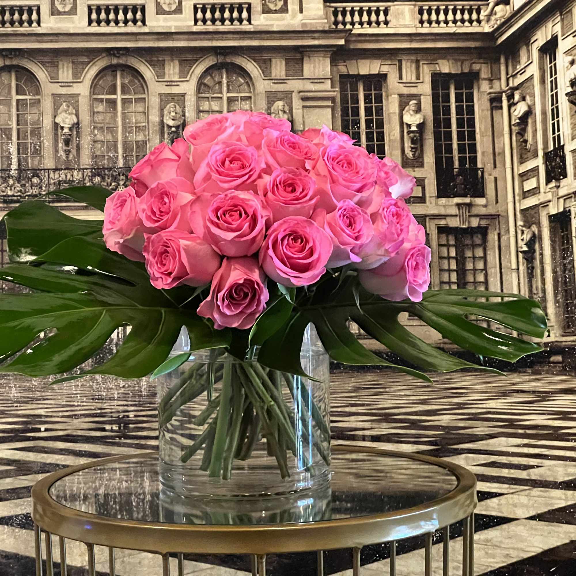 A modern bouquet of pink roses framed by monstera leaves