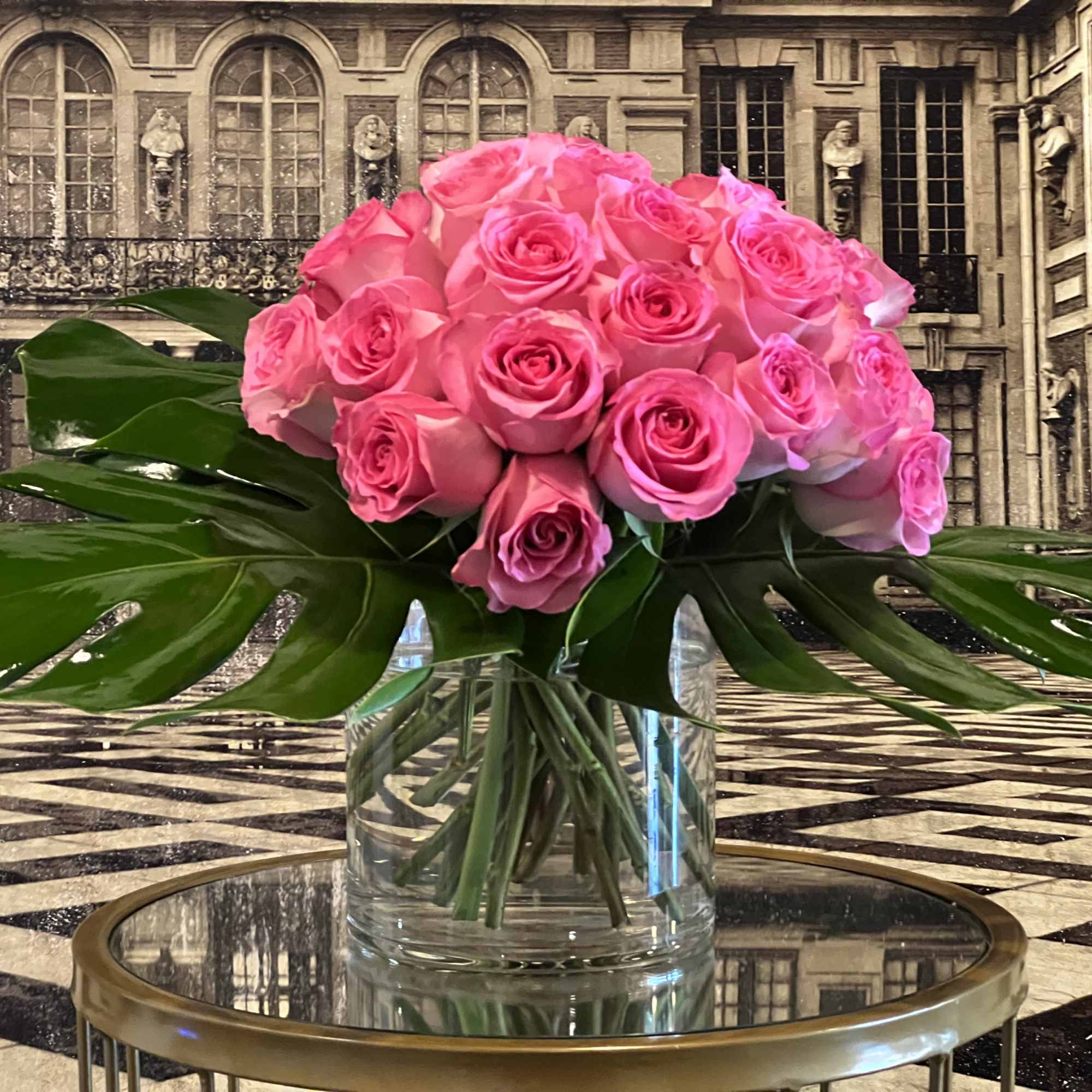 A modern bouquet of pink roses framed by monstera leaves