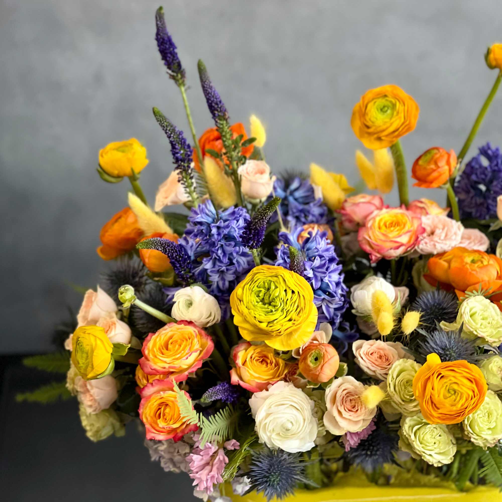 The design features elegant splashes of yellow ranunculus, orange, peach and white